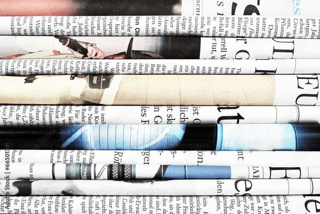 Zusammengerollte Zeitungen mit Abschnitten mit Schlagzeilen und Artikeln.