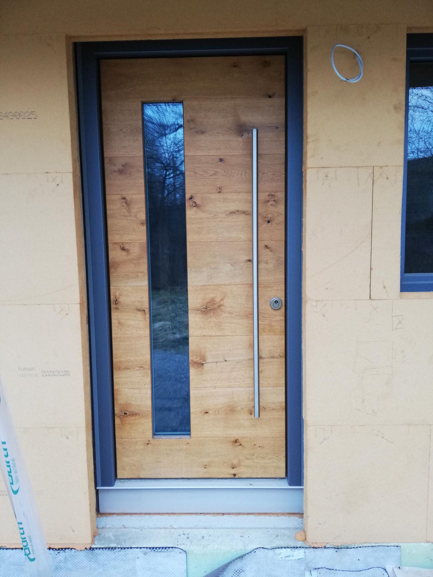 Eine moderne Vollholztür mit einer länglichen Glasscheibe