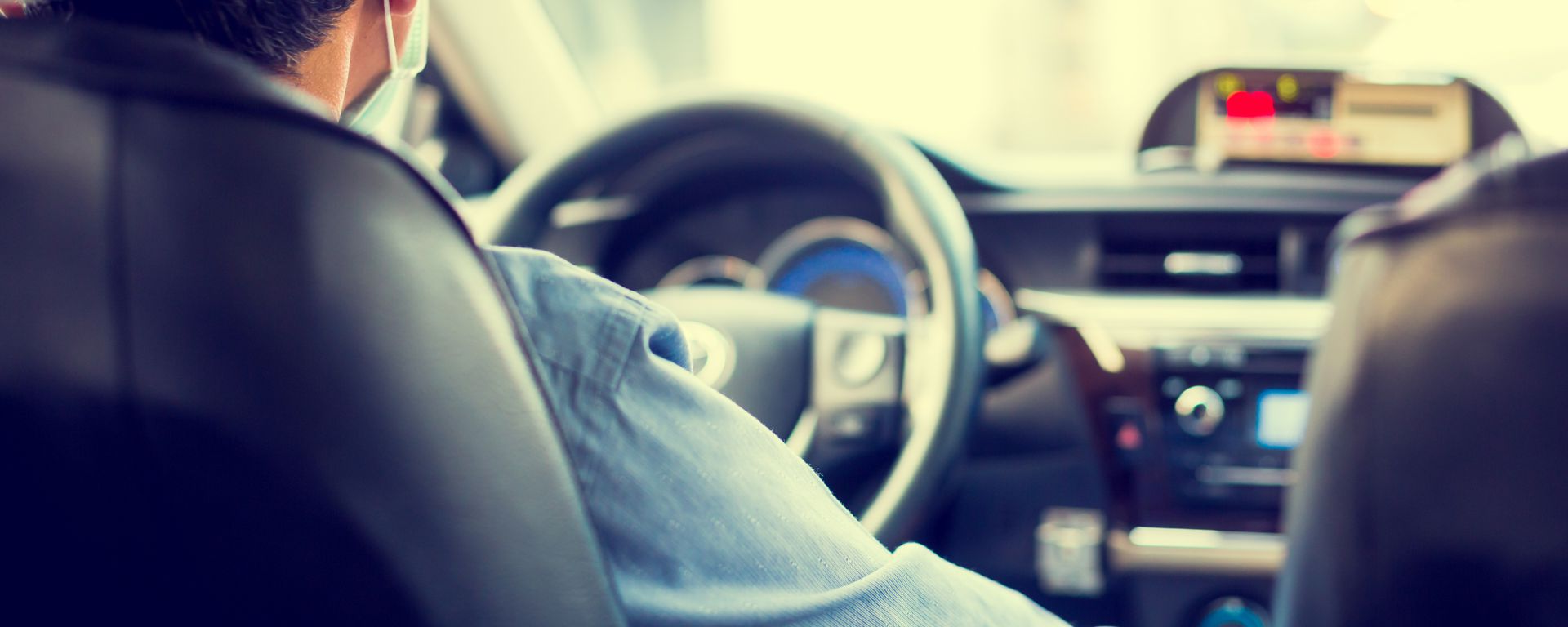 Une personne portant un masque facial conduit un taxi.