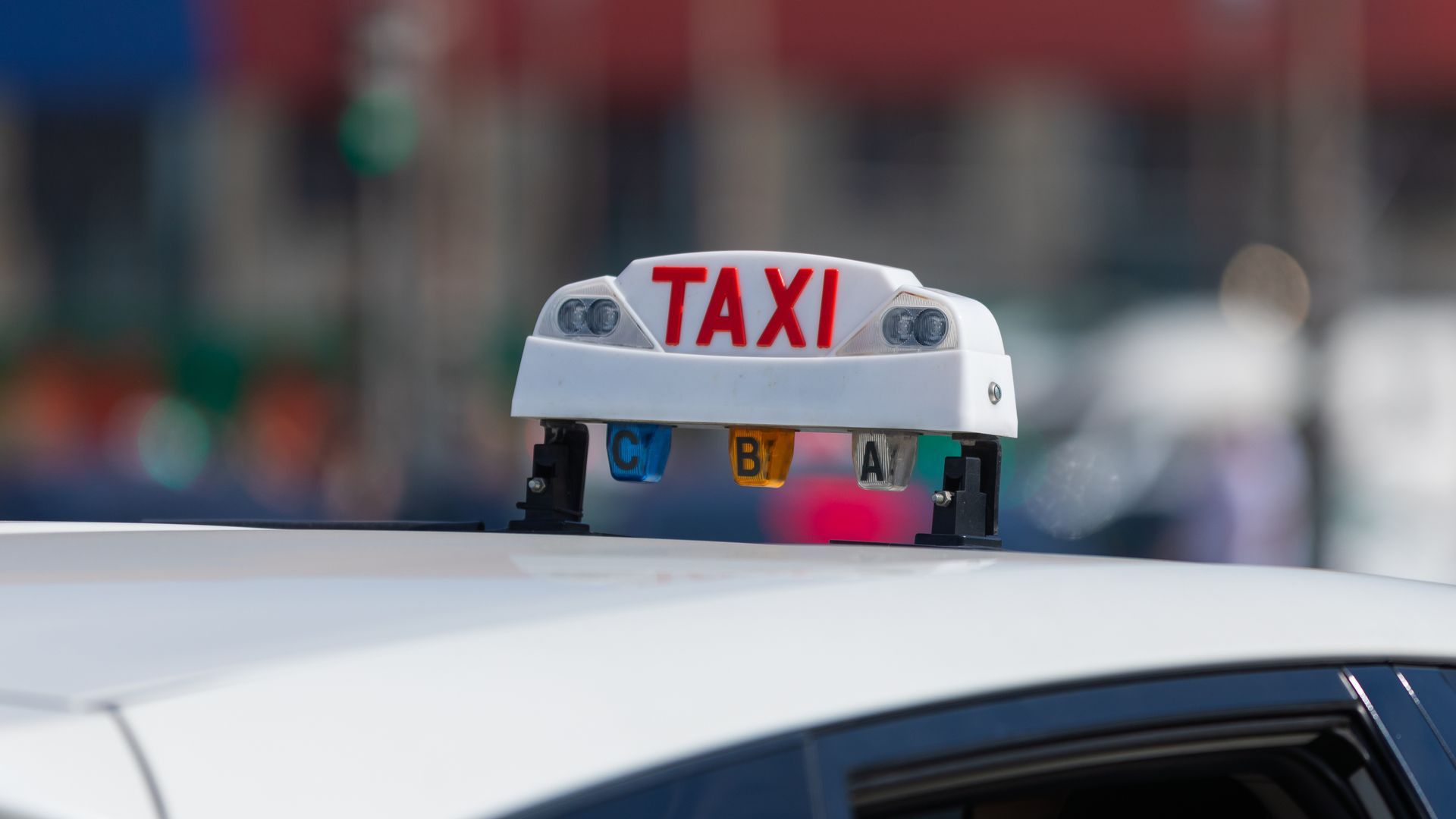 Panneau de toit de taxi blanc avec TAXI rouge sur le dessus d'une voiture blanche.