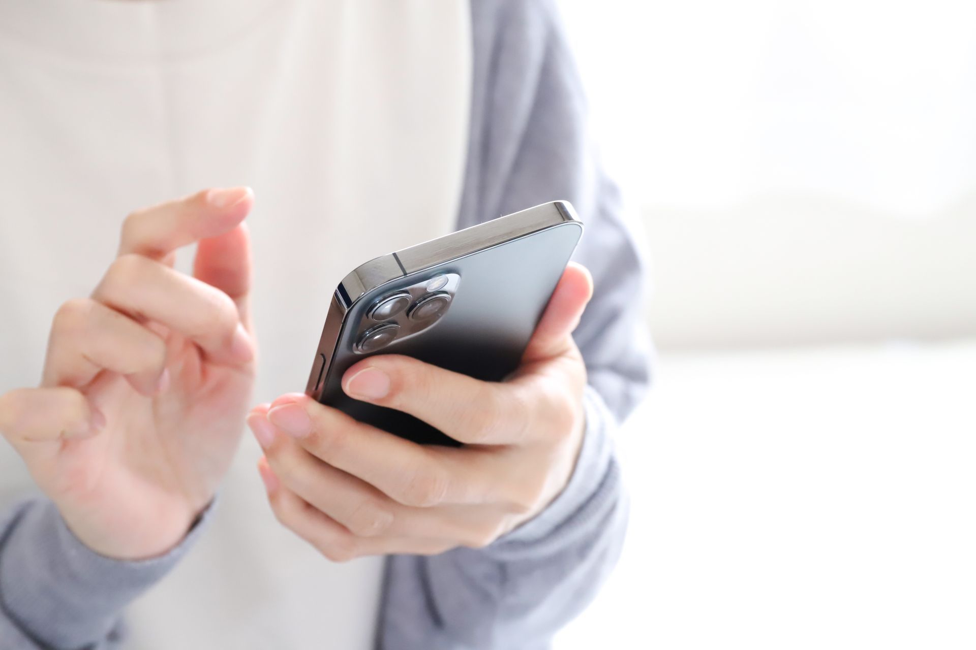 Personne tenant un smartphone, utilisant ses doigts pour interagir avec l'écran.