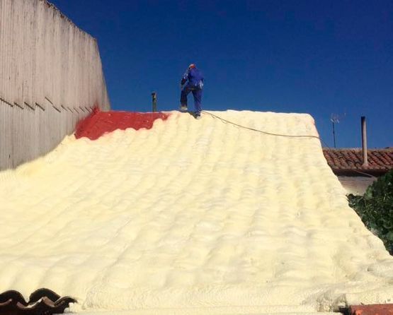Un hombre está parado encima de una pila de espuma en un techo.
