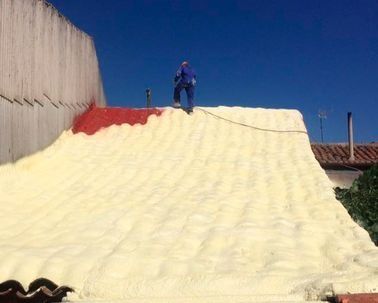 Un hombre está parado encima de una pila de espuma en un techo.