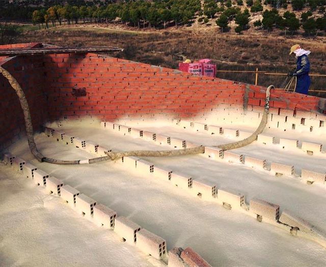 Un techo rojo con una pared de ladrillos y edificios al fondo.
