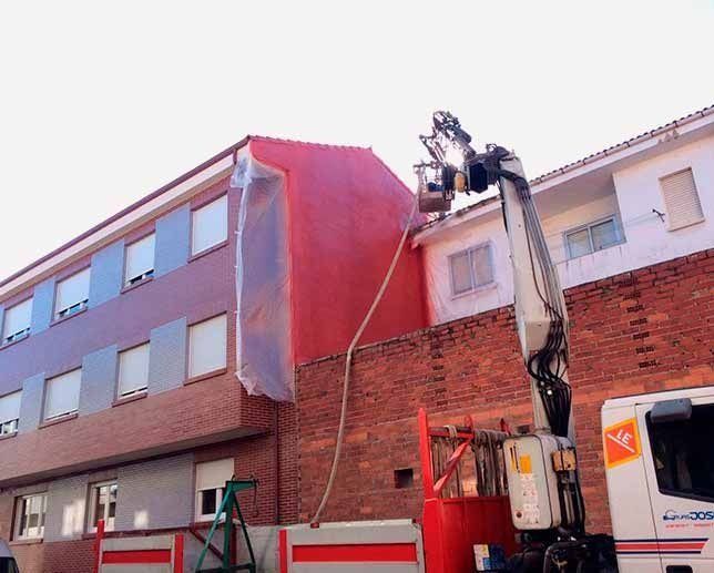 Se está utilizando una grúa para pintar el lateral de un edificio.