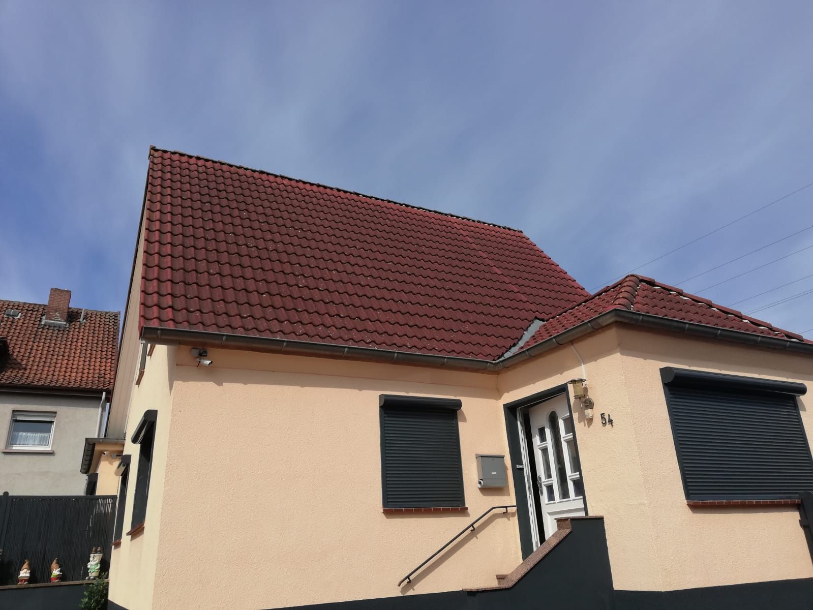 Ein Haus mit einem roten Ziegeldach und schwarzen Fensterläden