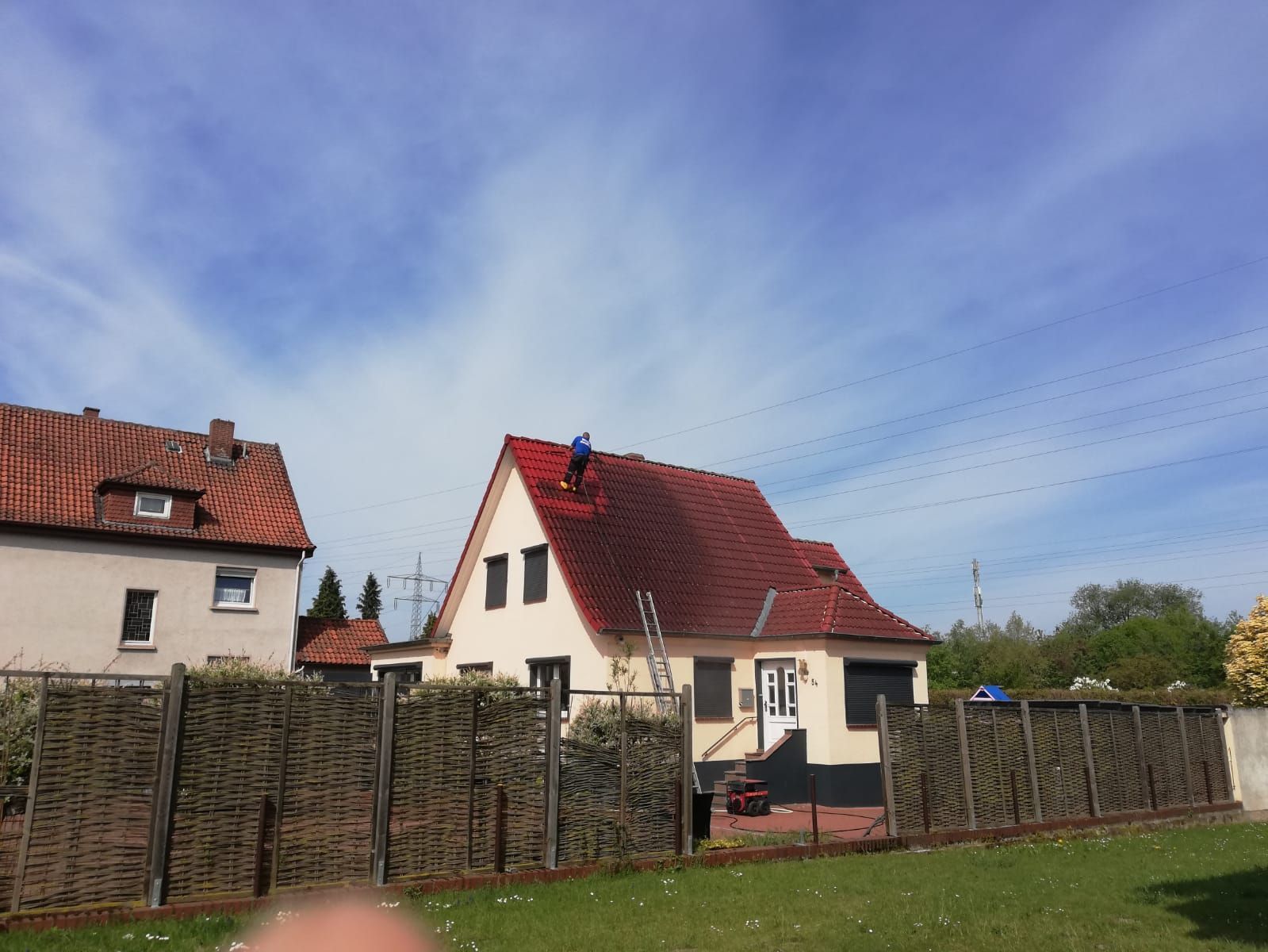 Ein Mann säubert das Dach eines Hauses.