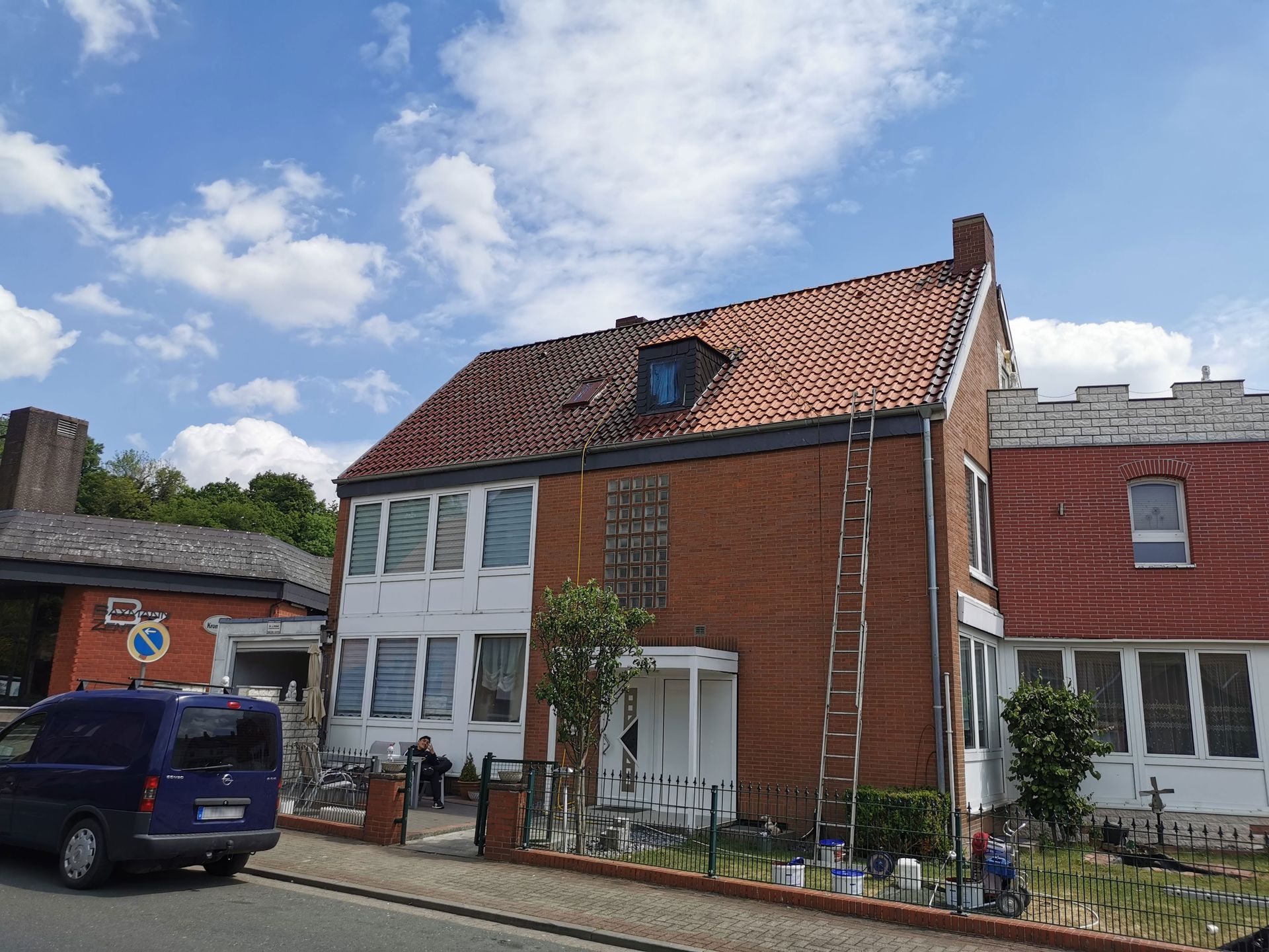 Ein Backsteinhaus, vor dem ein blauer Lieferwagen geparkt ist.