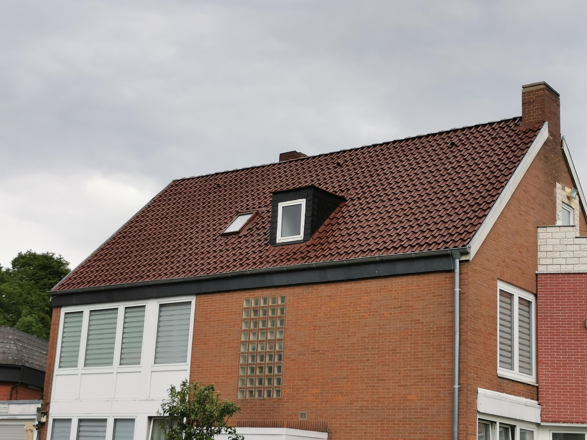 Ein Backsteinhaus mit einem roten Dach und einem Oberlicht