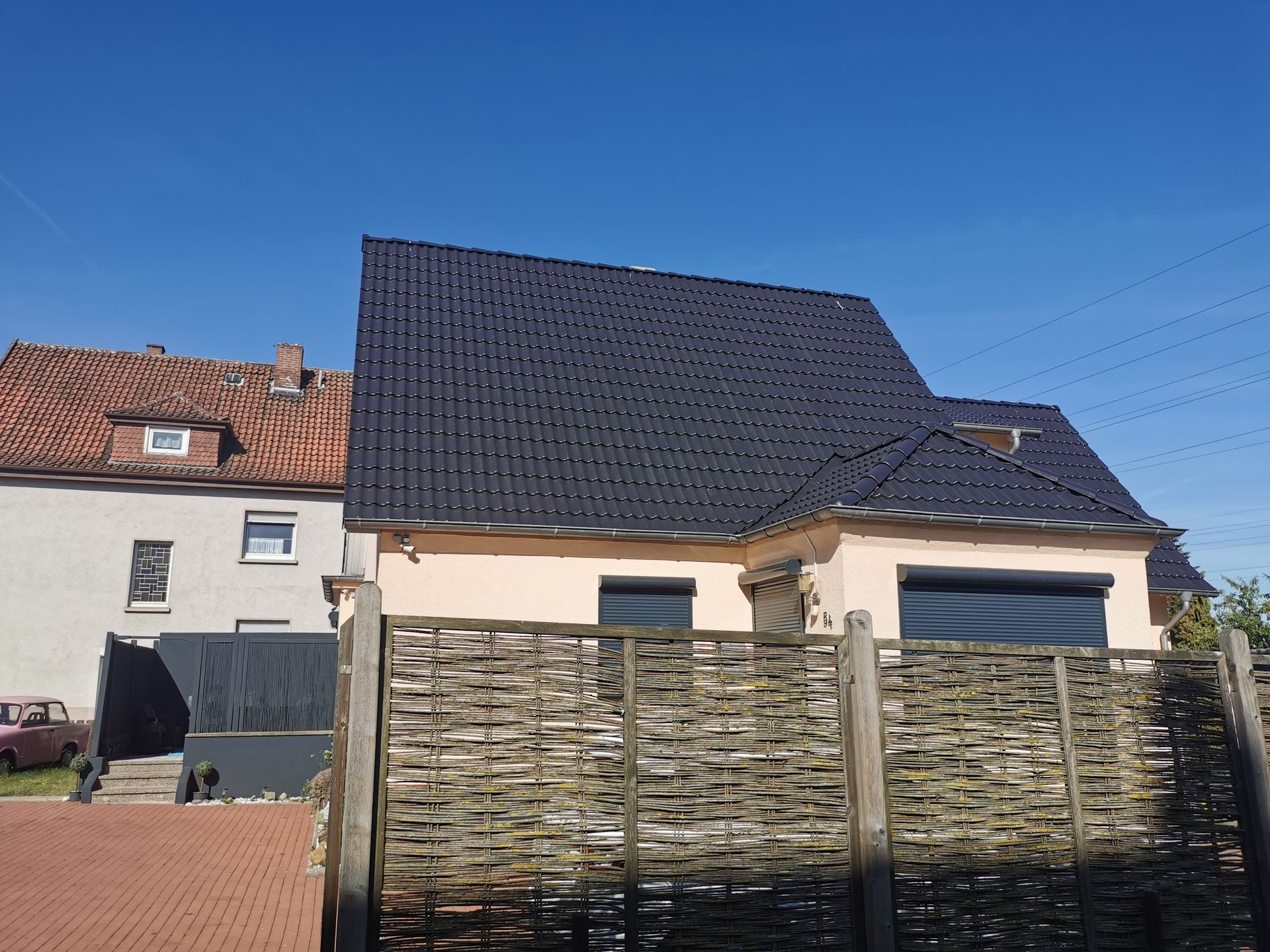 Ein Haus mit einem schwarzen Dach und einem Holzzaun davor.