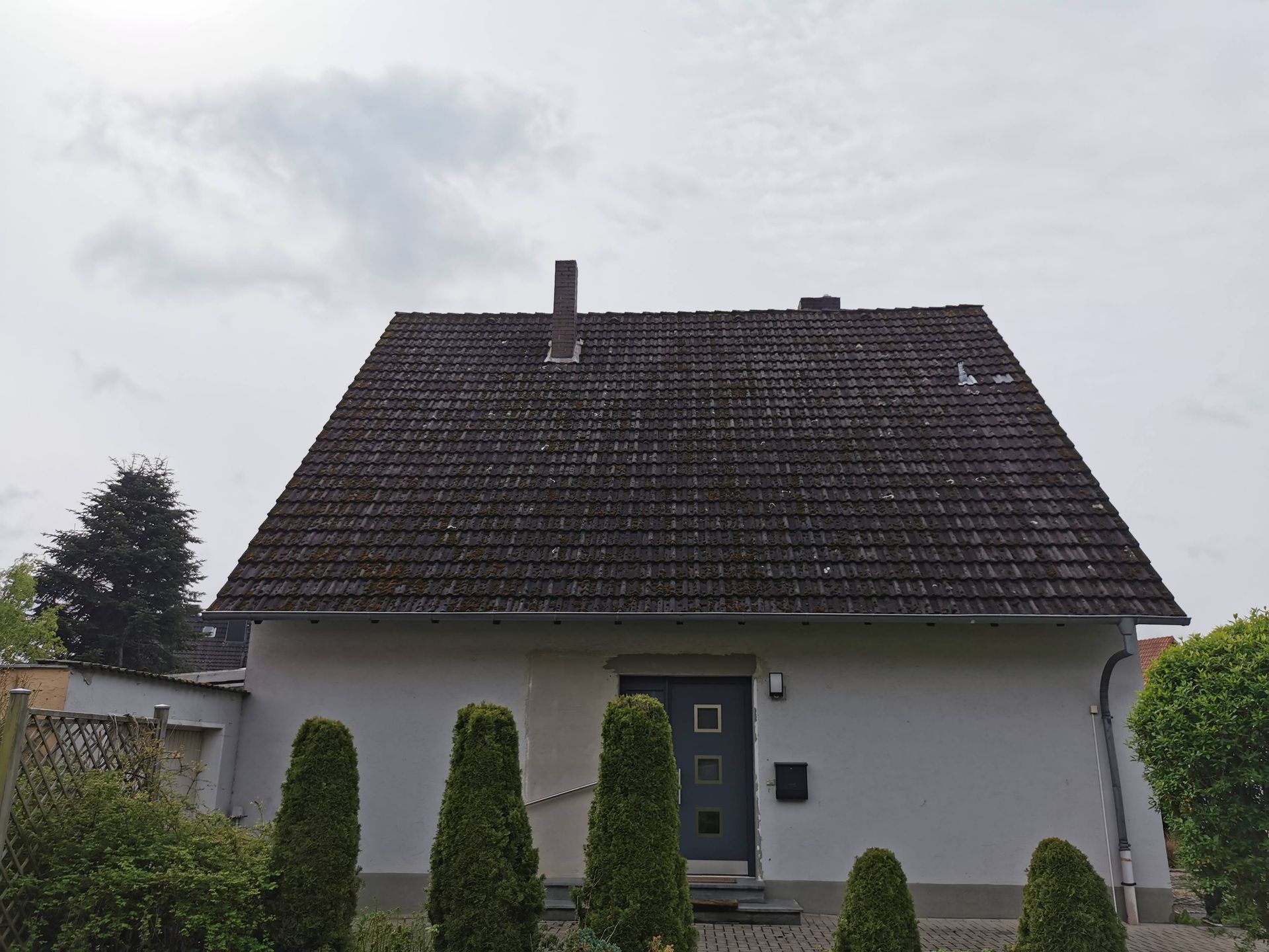 Ein weißes Haus mit einem schwarzen Dach und einer schwarzen Tür