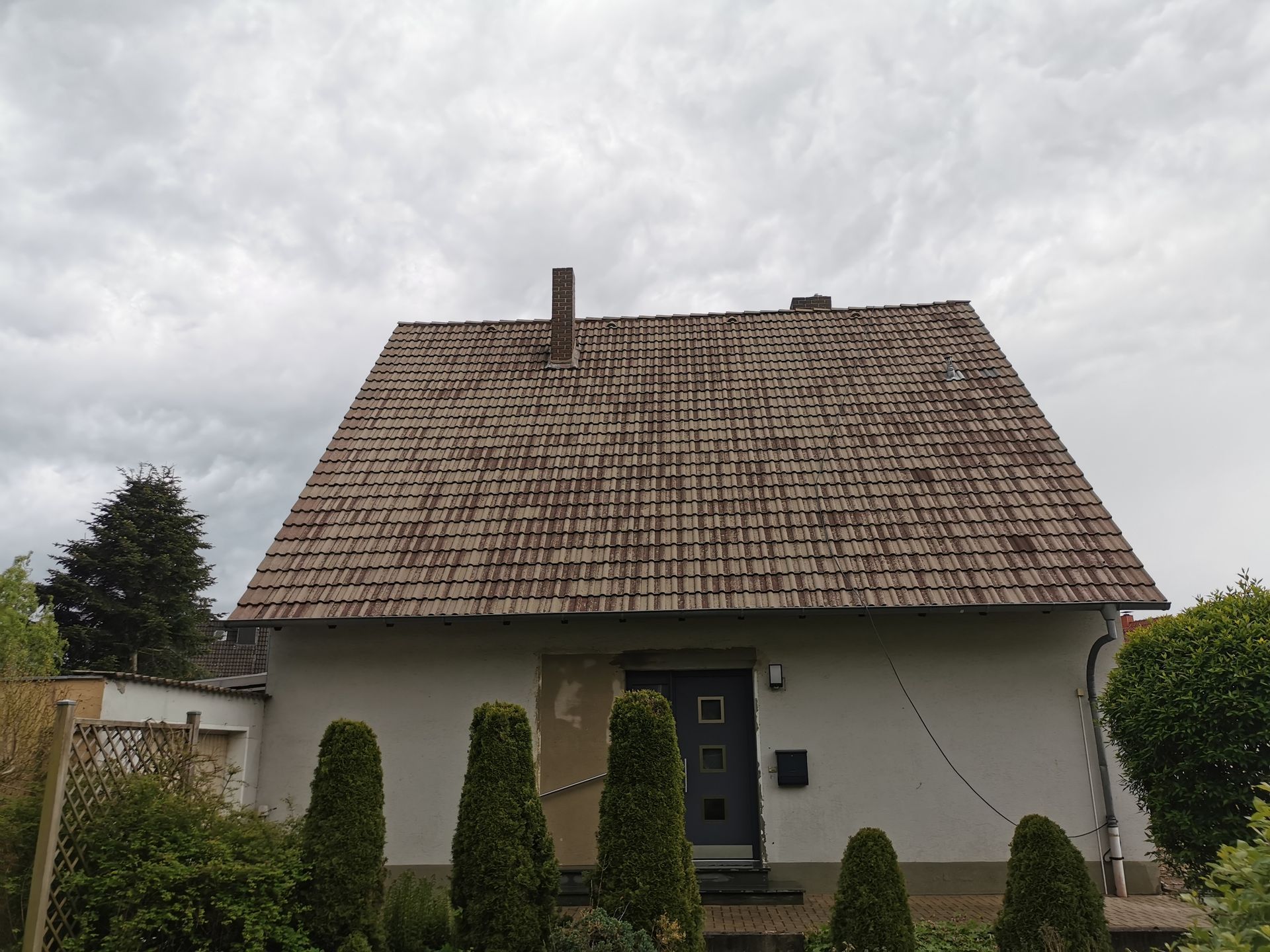 Ein weißes Haus mit einem Holzdach und einem Schornstein
