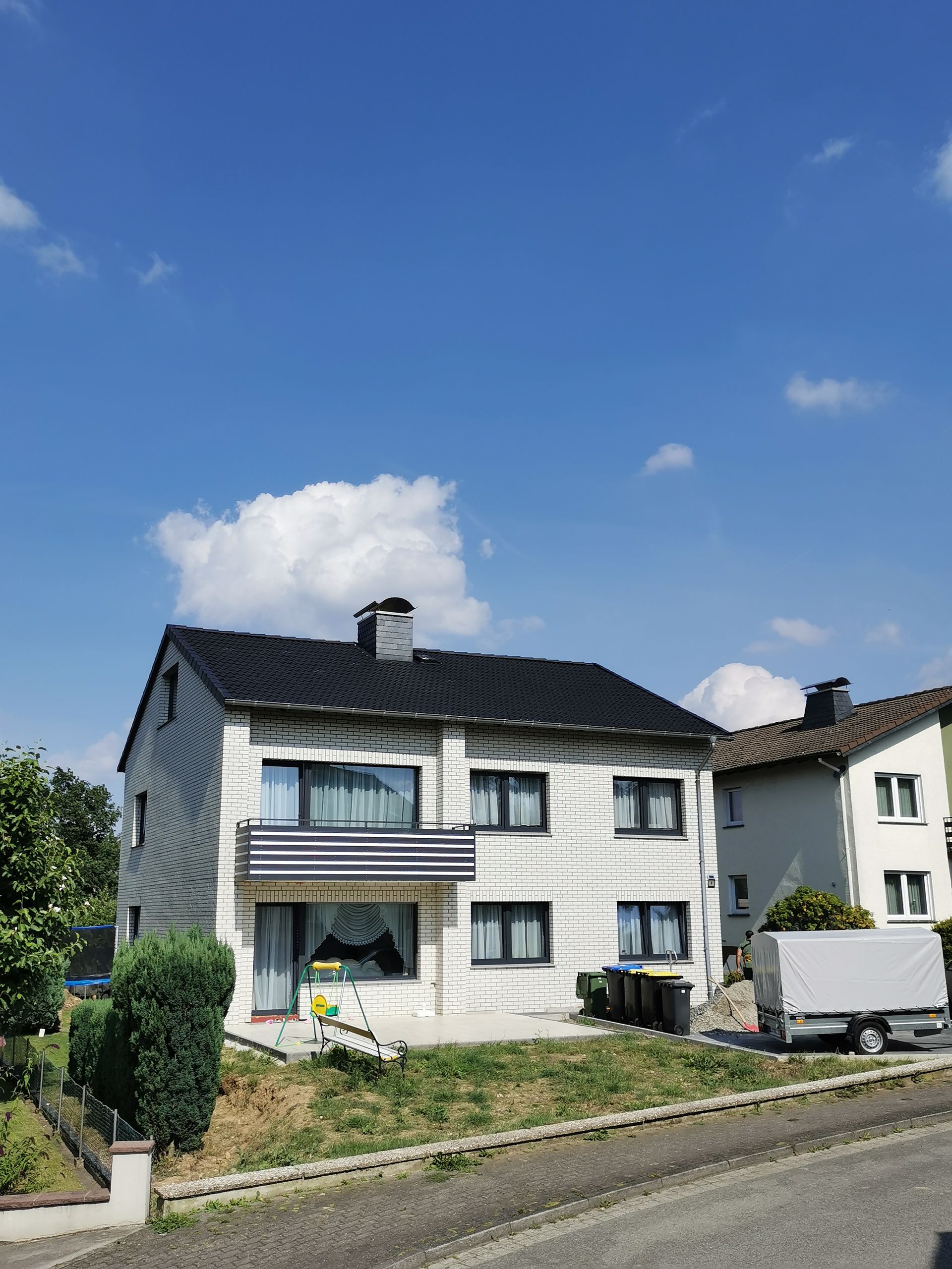 Auf einem Hügel steht ein weißes Haus mit schwarzem Dach.