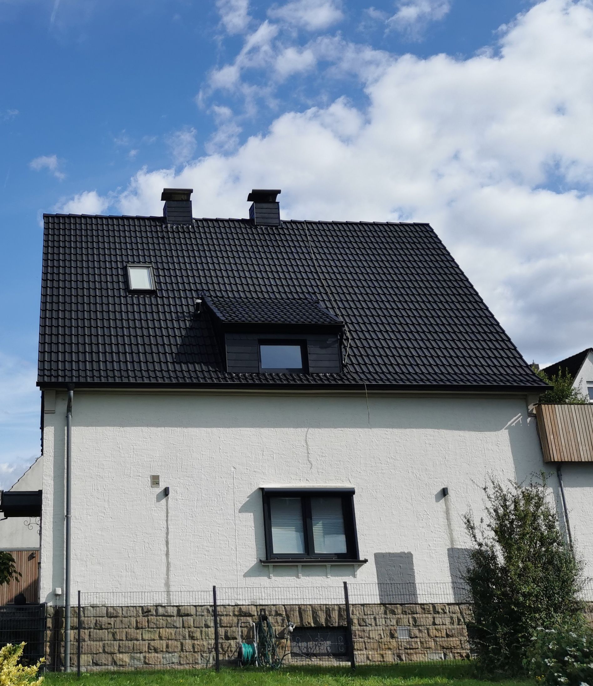 Ein weißes Haus mit einem schwarzen Dach und einem Fenster