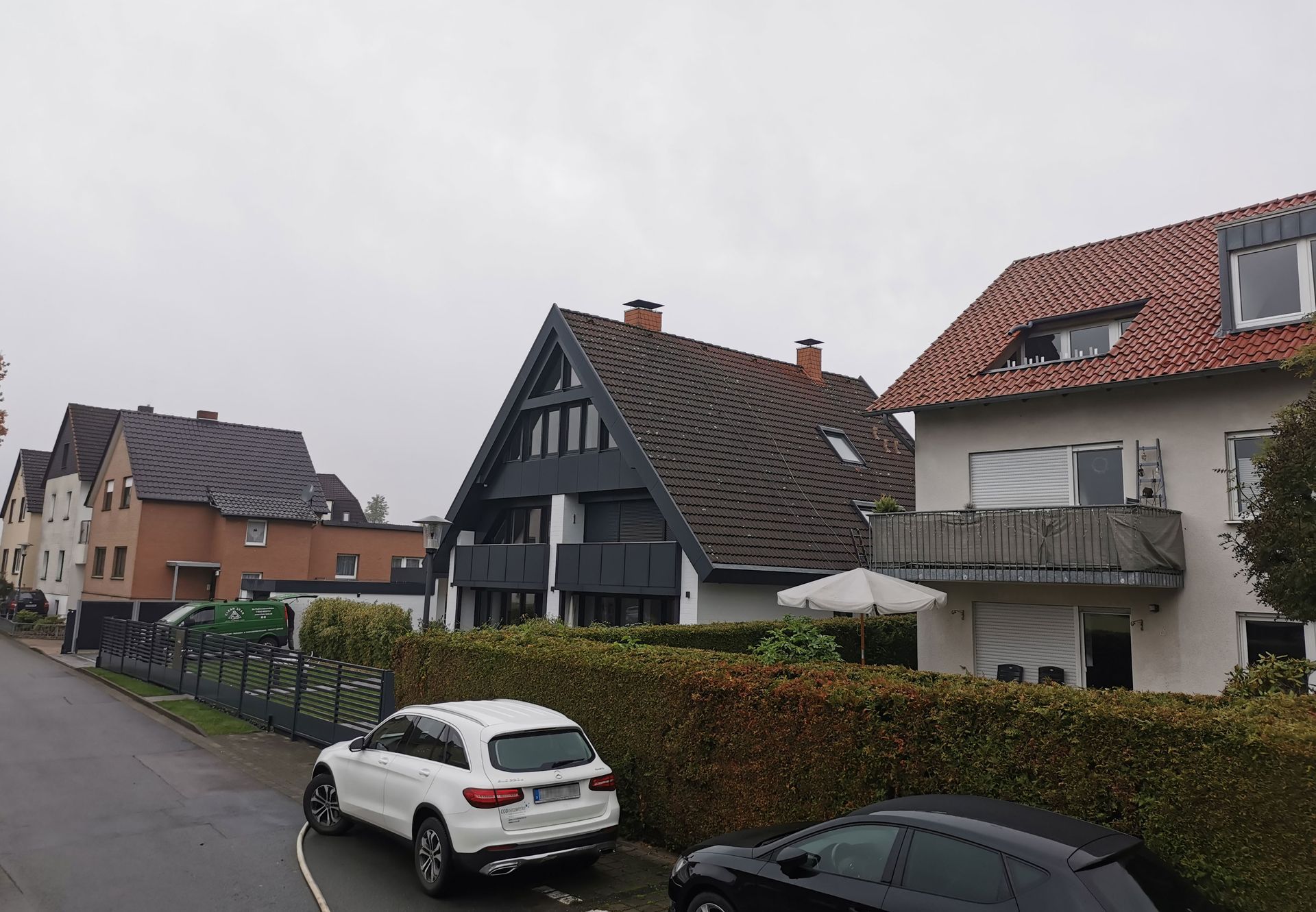 Vor einer Häuserreihe parkt ein weißer SUV.