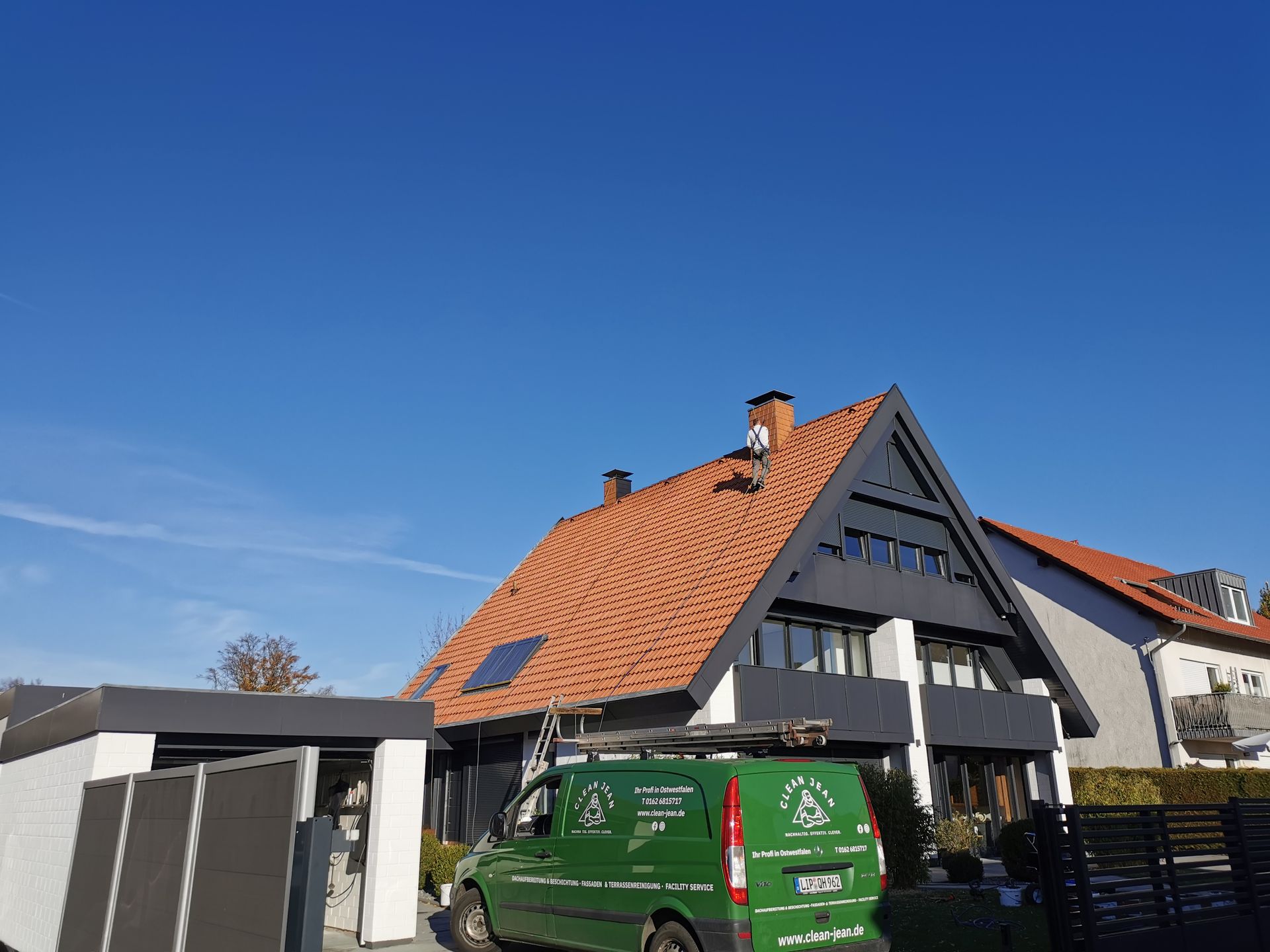 Ein grüner Lieferwagen parkt vor einem Haus mit einem roten Ziegeldach.