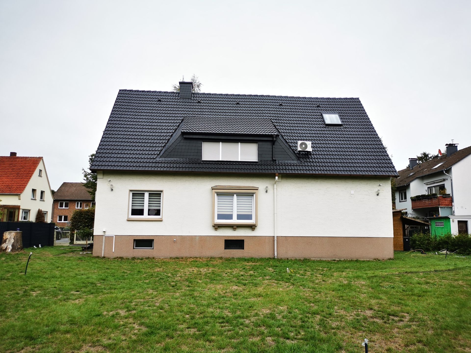 Ein weißes Haus mit einem schwarzen Dach und vielen Fenstern