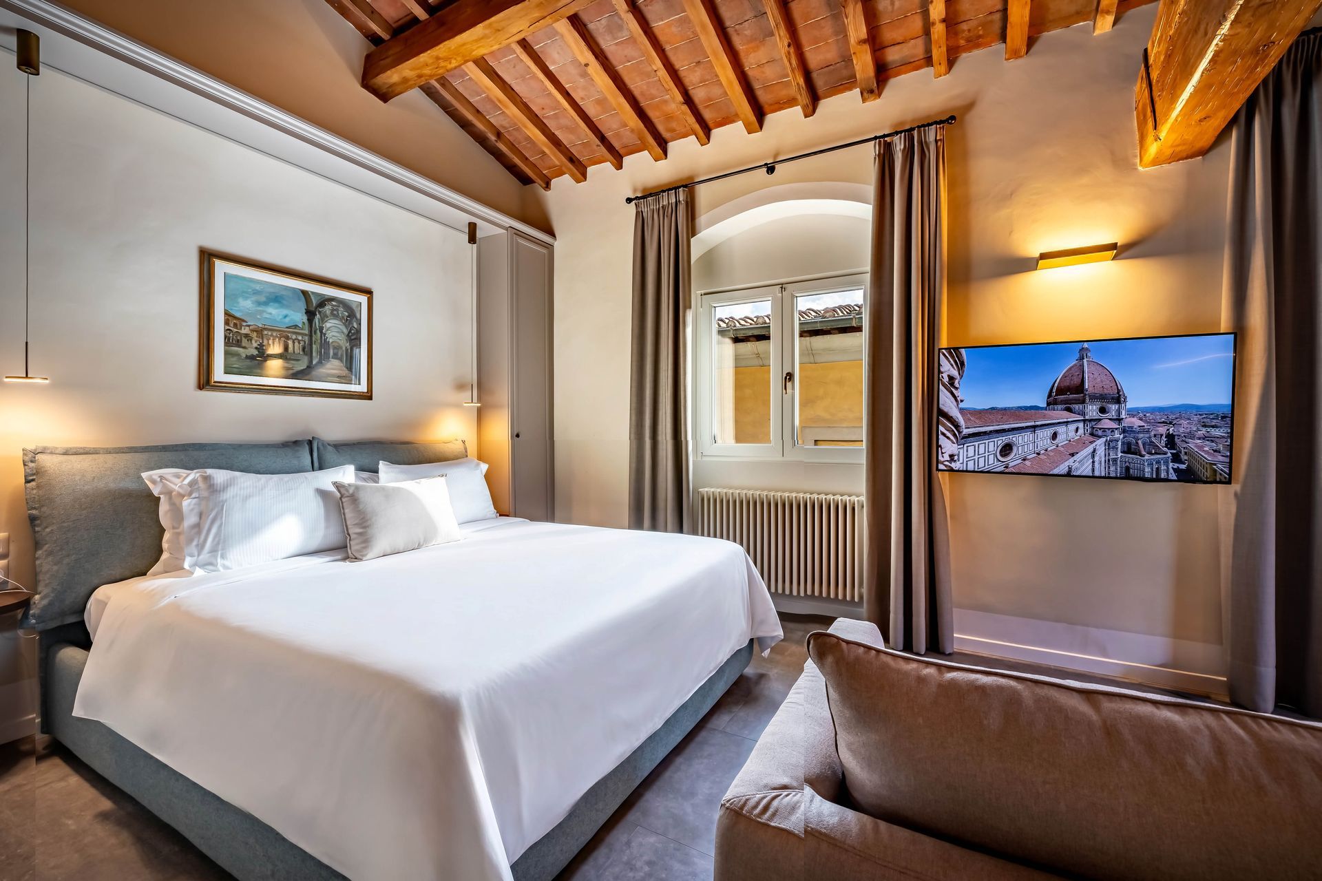 Le Torri by Dimora Collection: Cozy bedroom with wooden ceiling, king bed, and wall-mounted TV in a warm-lit interior