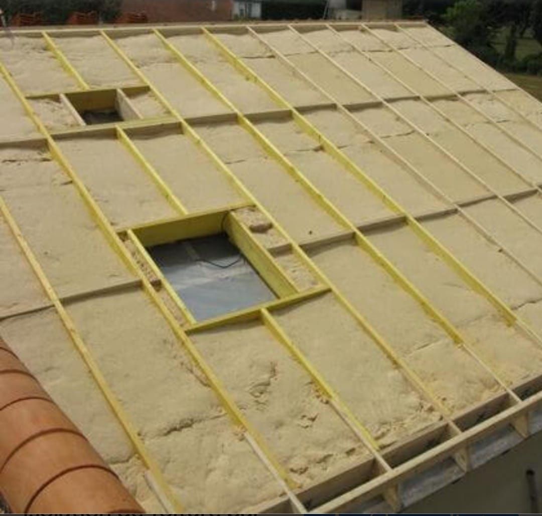 Toiture recouverte de panneaux isolants jaunes et percée de plusieurs ouvertures rectangulaires laissant apparaître la structure sous-jacente.