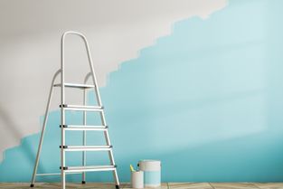 Leiter vor einer Wand, die schon teils hellblau gestrichen wurde