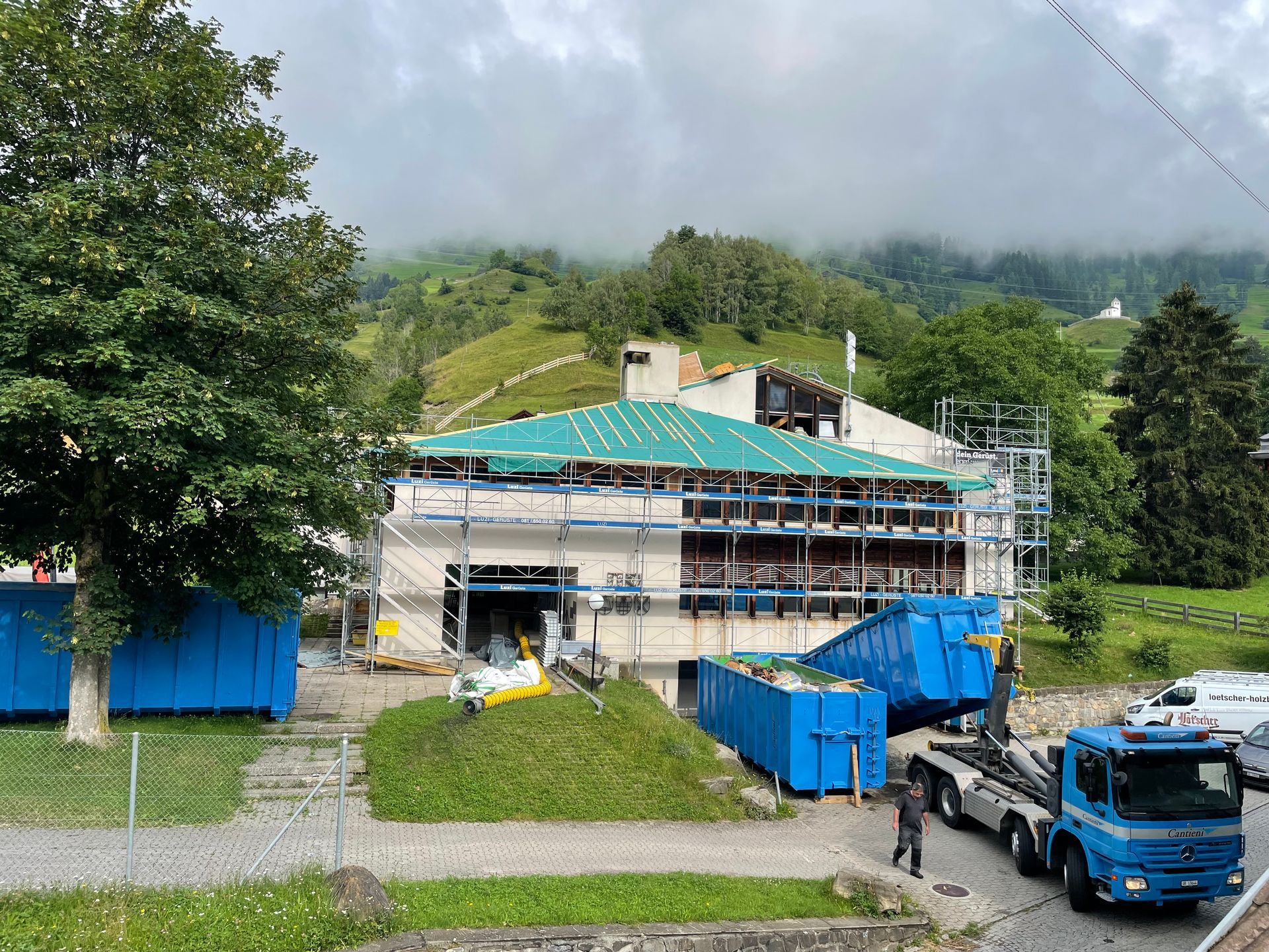 Ein blauer Lastwagen steht vor einem im Bau befindlichen Gebäude.