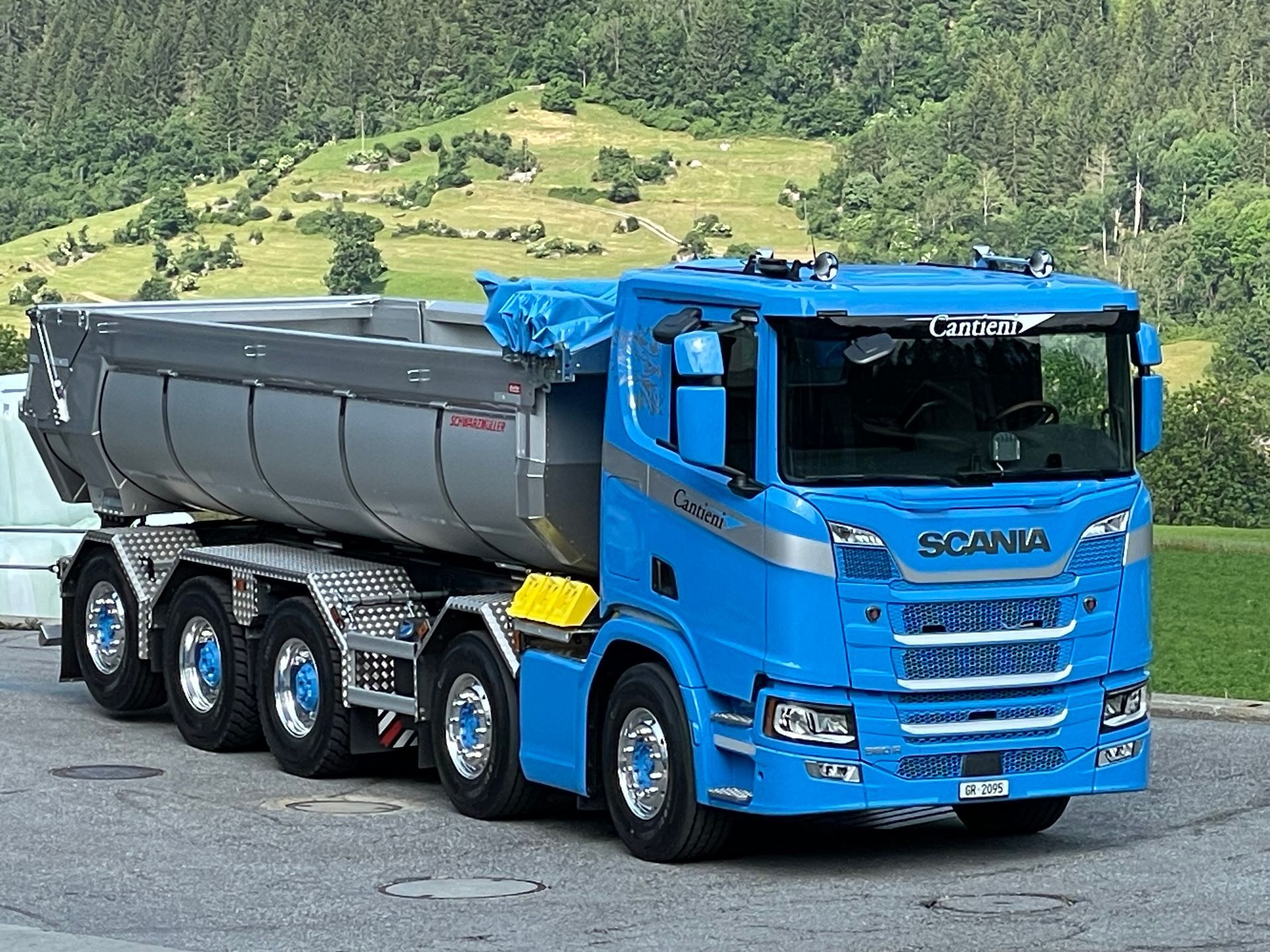 Vor einem Berg parkt ein blauer Muldenkipper.