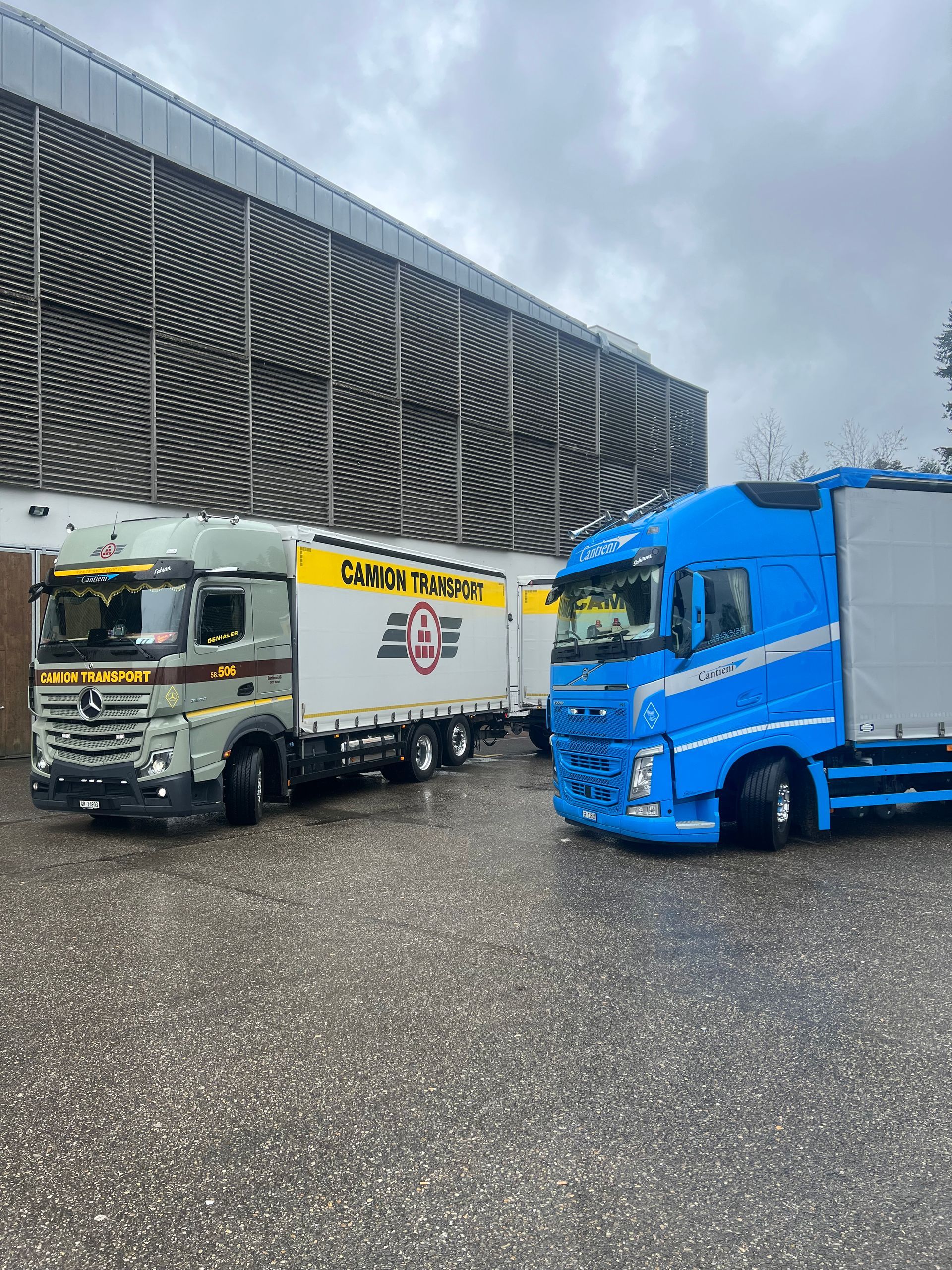 Zwei Lastwagen parken vor einem Gebäude.