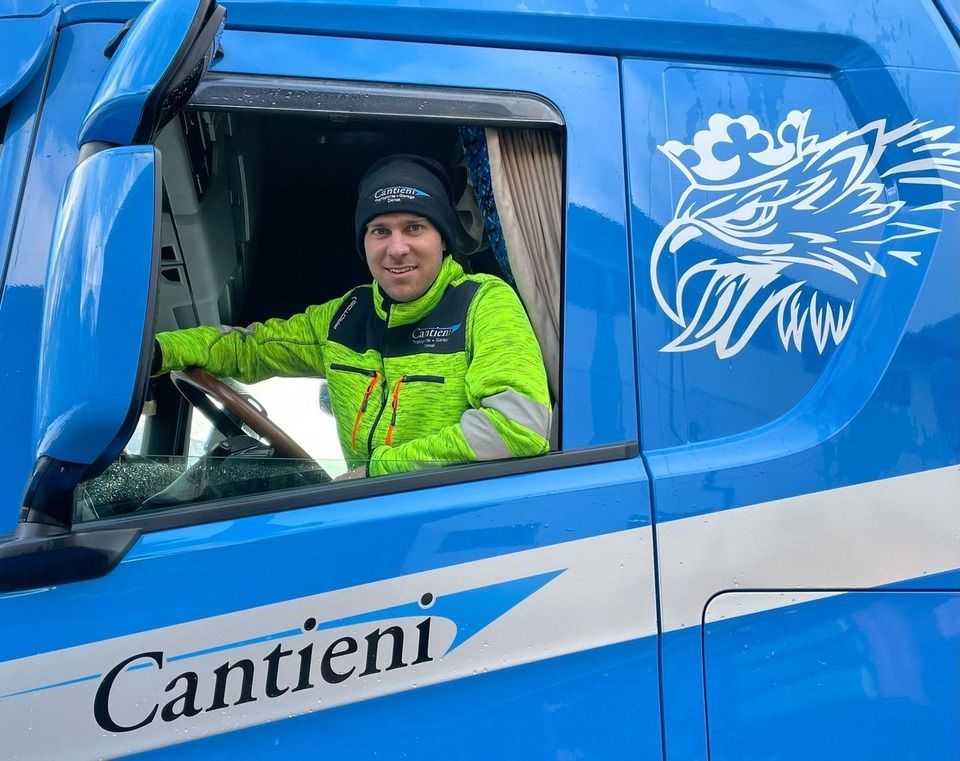 Ein Mann sitzt auf dem Fahrersitz eines blauen Lastwagens.