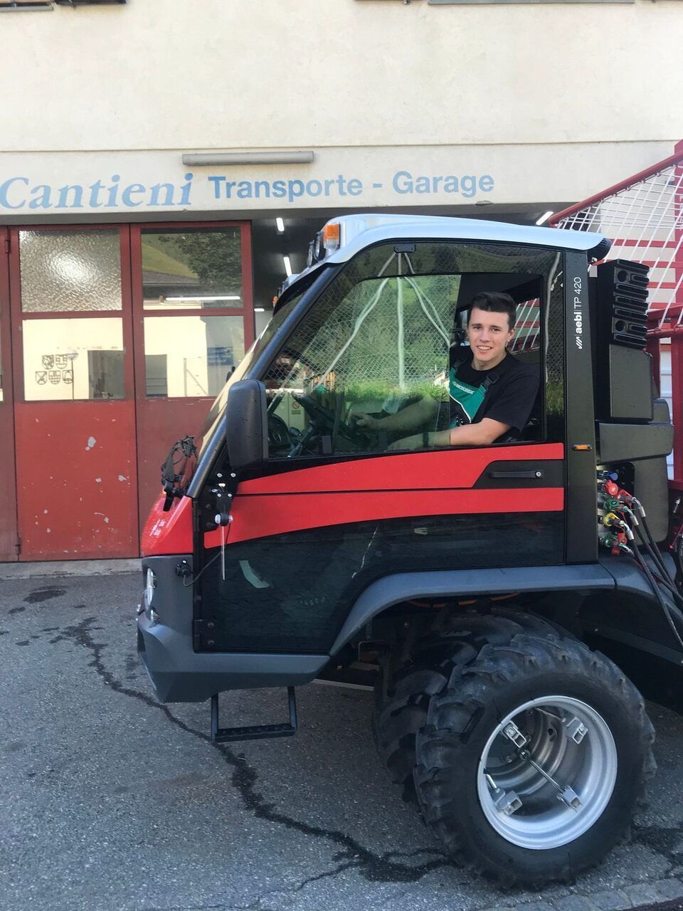 Ein Mann sitzt in einem roten LKW vor einer Cantieni-Transporte-Garage