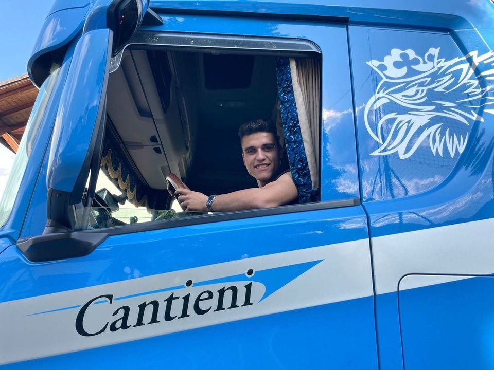 Ein Mann sitzt auf dem Fahrersitz eines blauen Lastwagens.