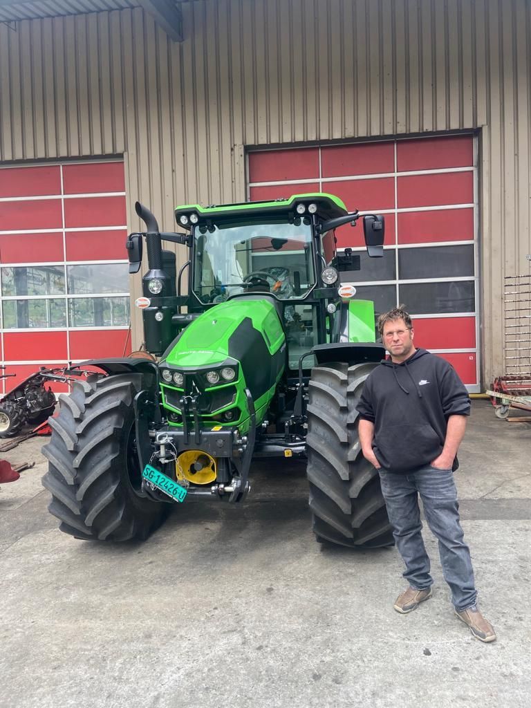 Ein Mann steht vor einem grünen Traktor.