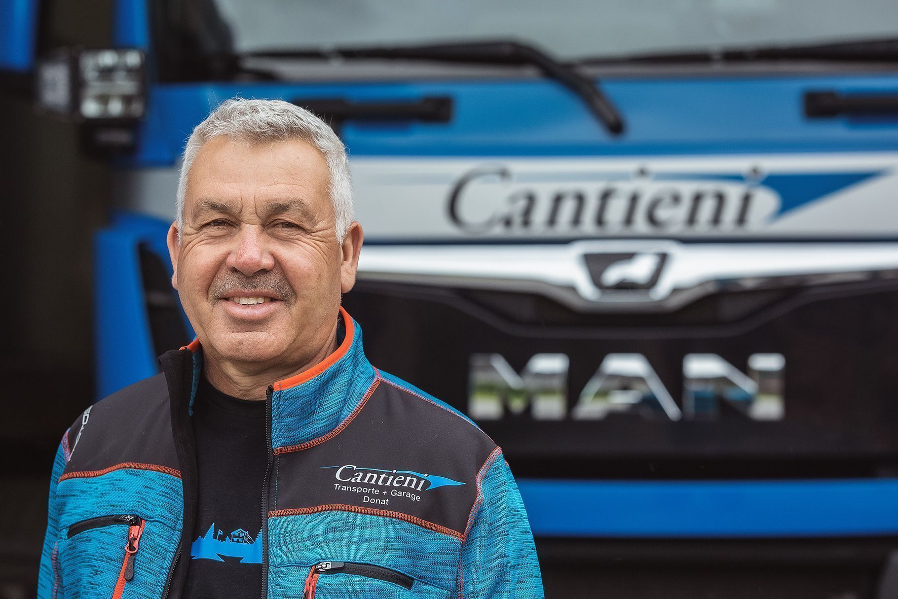 Ein Mann steht vor einem blauen Lastwagen.