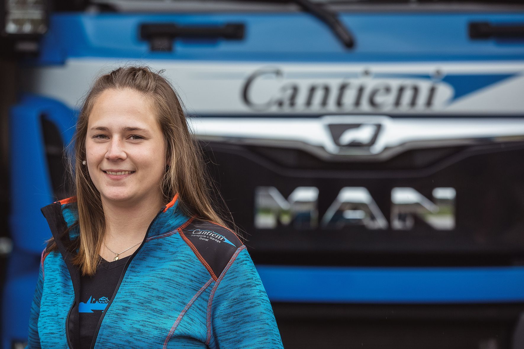 Eine Frau steht vor einem blauen Lastwagen.