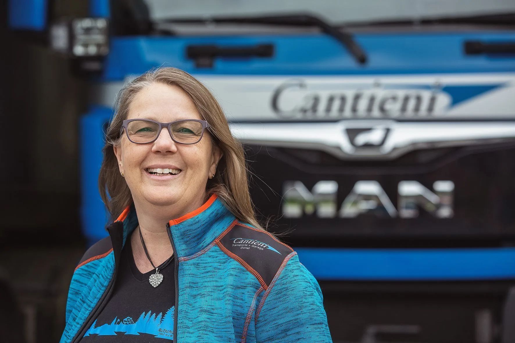 Eine Frau steht vor einem blauen Lastwagen.