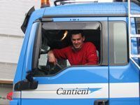 Ein Mann sitzt auf dem Fahrersitz eines blauen Lastwagens.