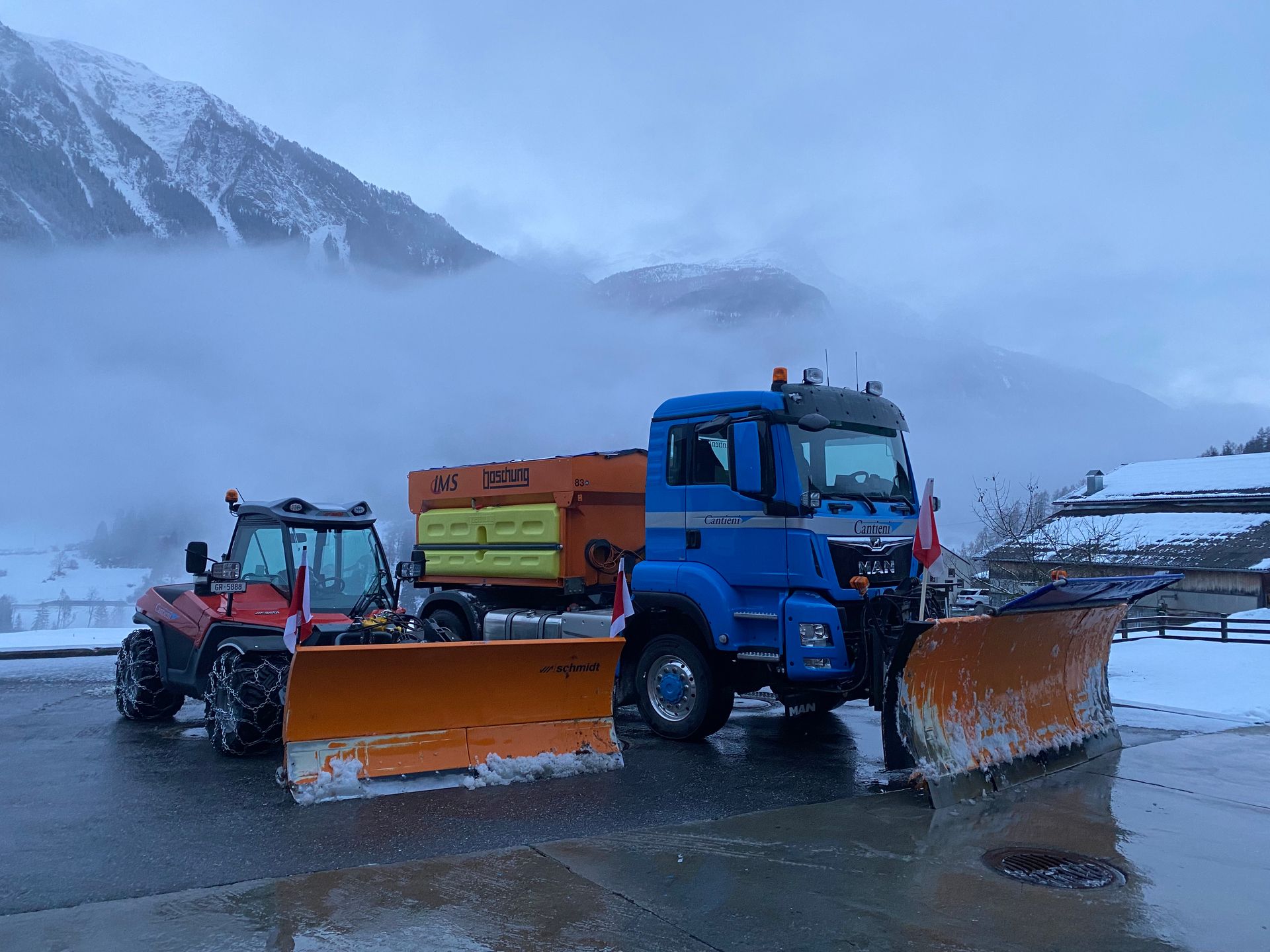 Auf einem Parkplatz stehen zwei Schneepflüge nebeneinander.