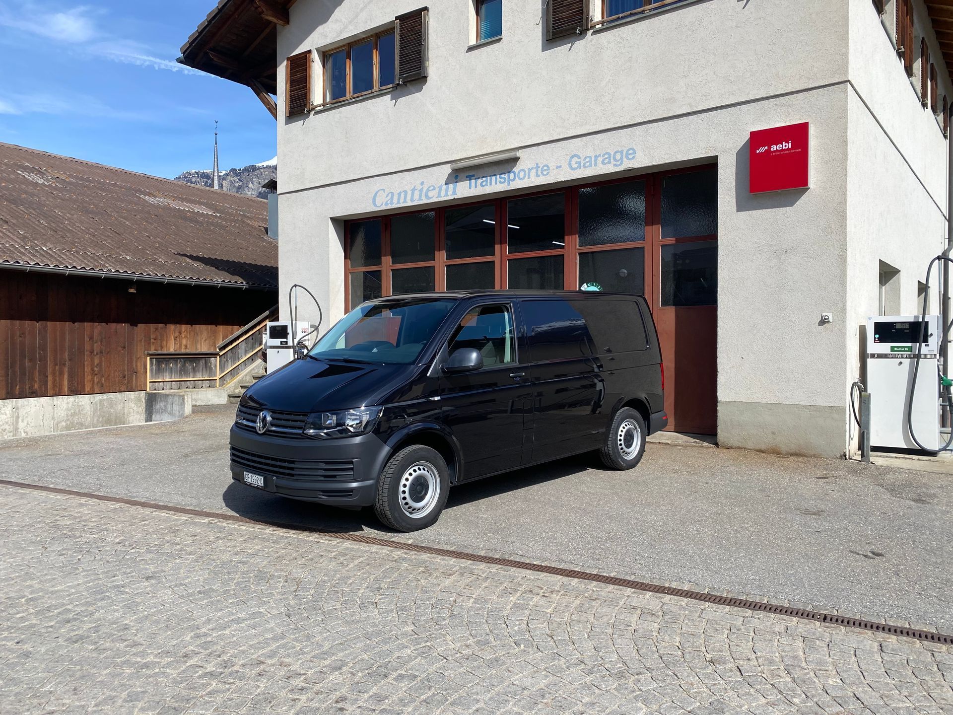 Vor einem Gebäude parkt ein schwarzer Lieferwagen.
