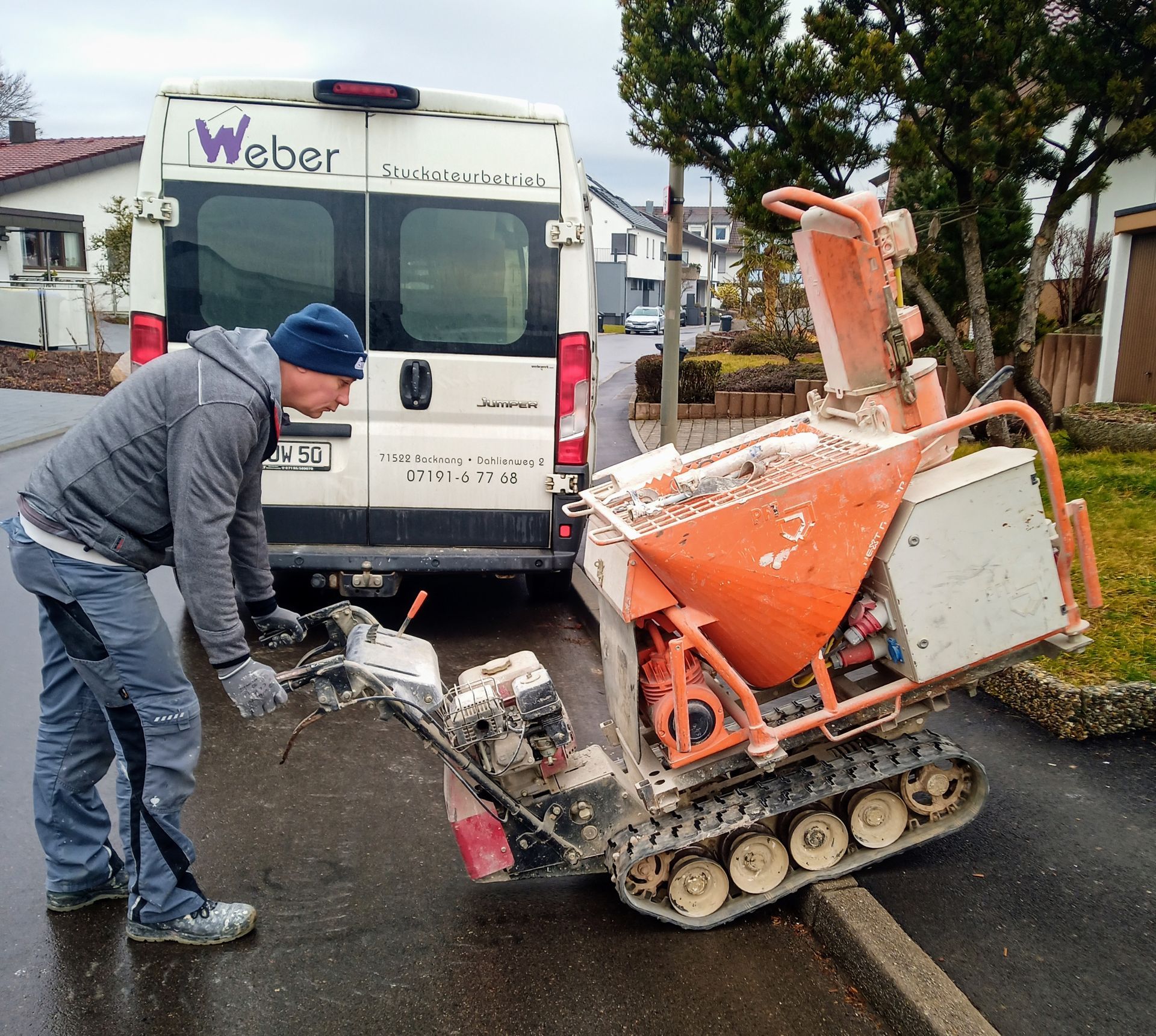 Ein Mann schiebt eine Maschine vor einen Weber-Transporter