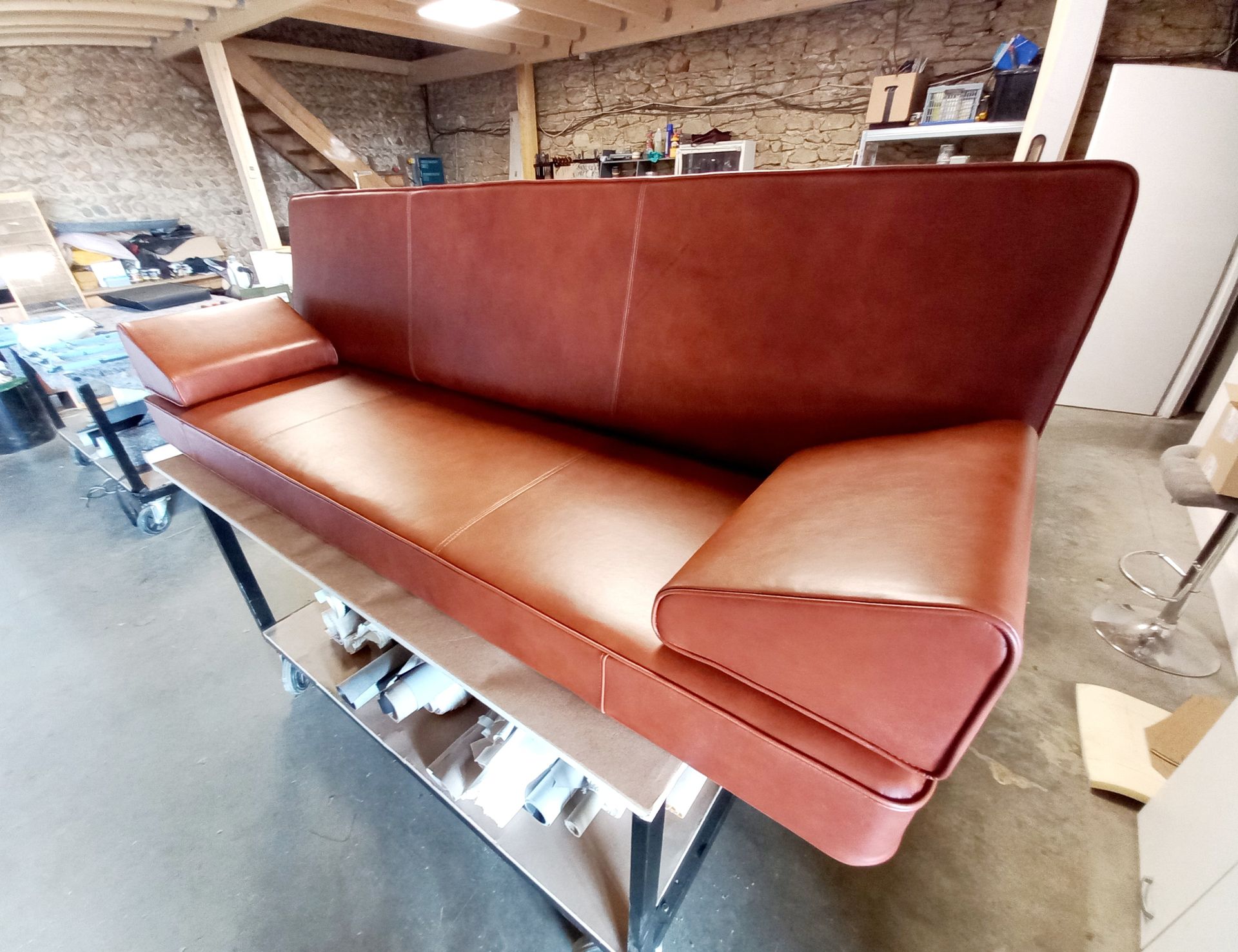 Banquette en cuir marron dans un atelier ou un espace de stockage, vue de côté.