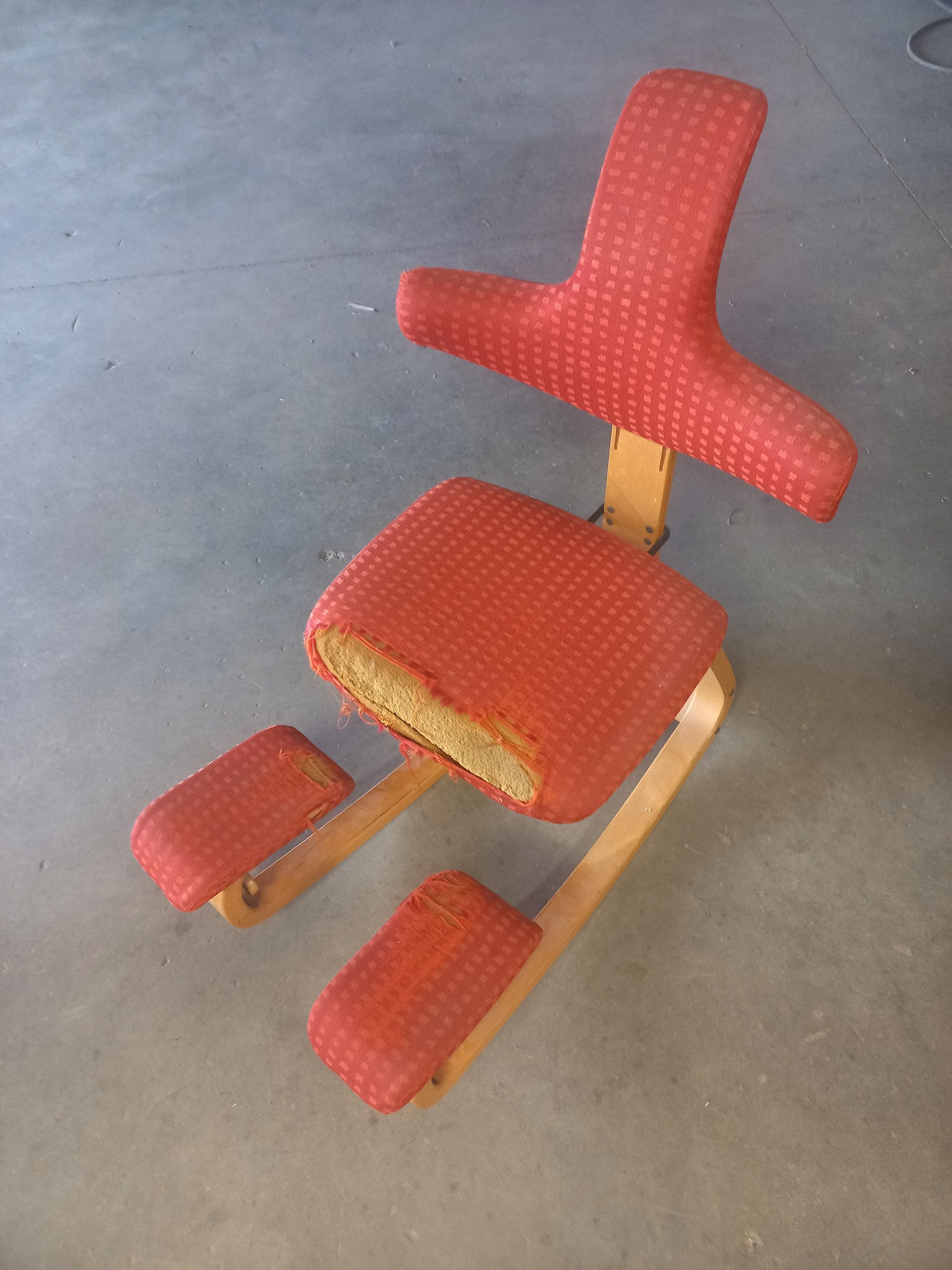 Chaise à genoux rouge rembourrée avec cadre en bois sur un sol gris
