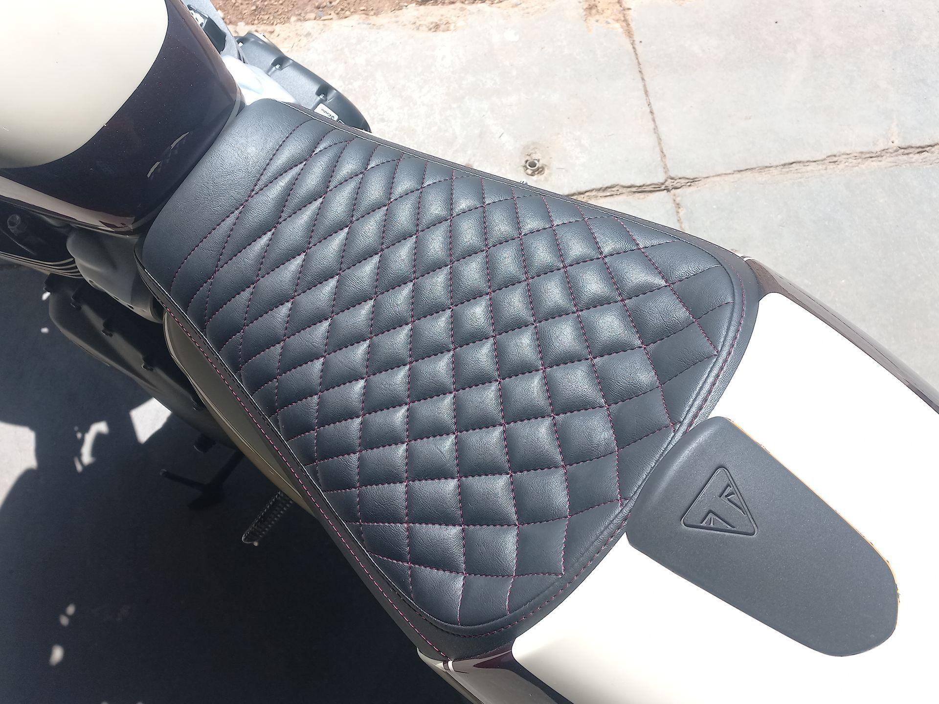 Selle de moto matelassée noire avec panneau arrière gris sur une moto garée sur le trottoir