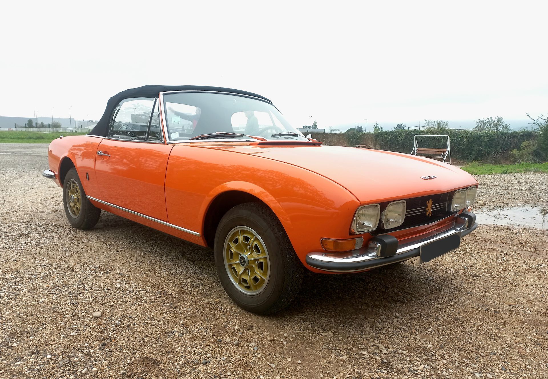 Voiture de sport décapotable orange vintage garée sur du gravier, vue de l'avant gauche