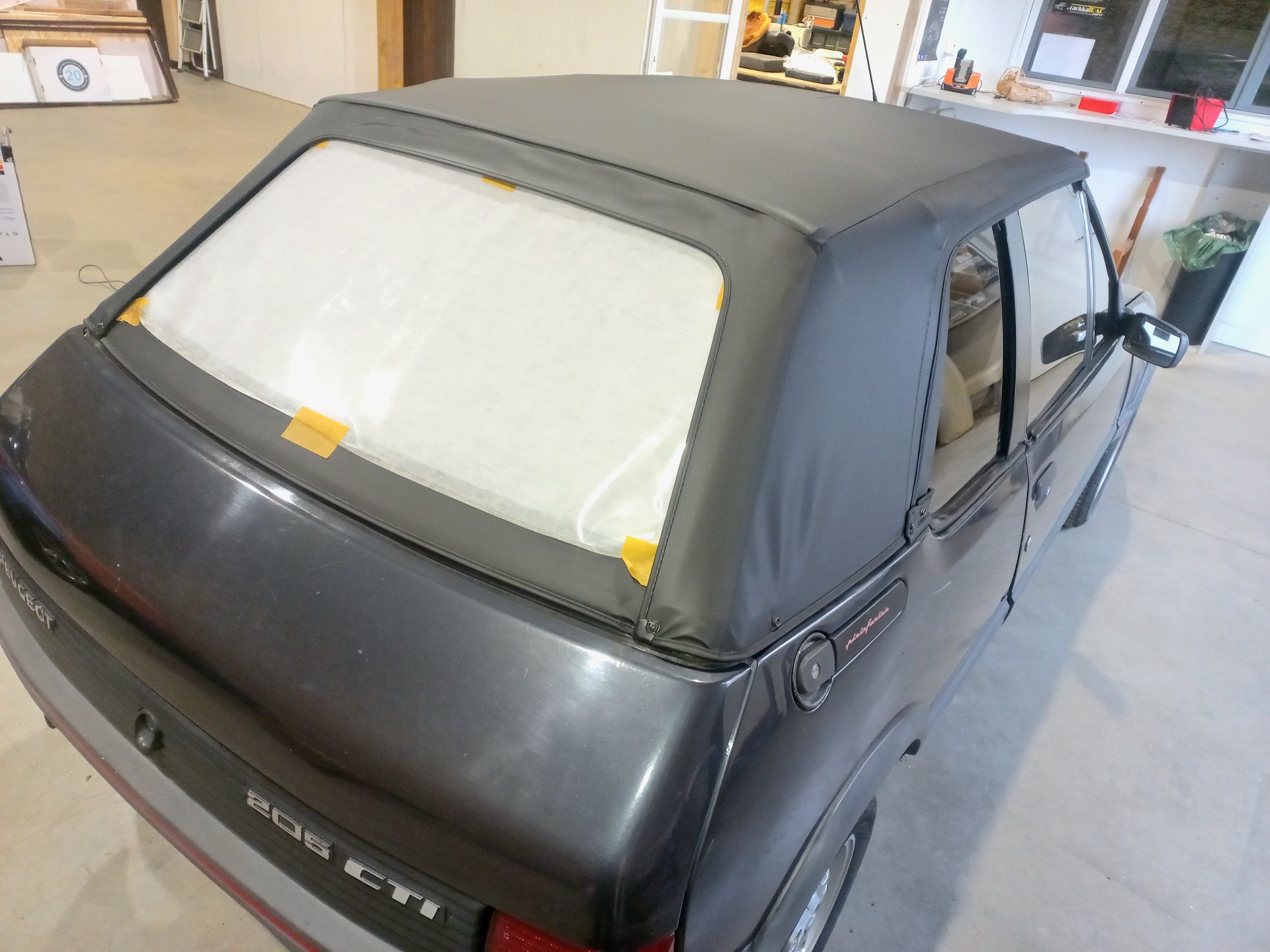 Voiture décapotable gris foncé dans un garage, vue de l'arrière gauche.