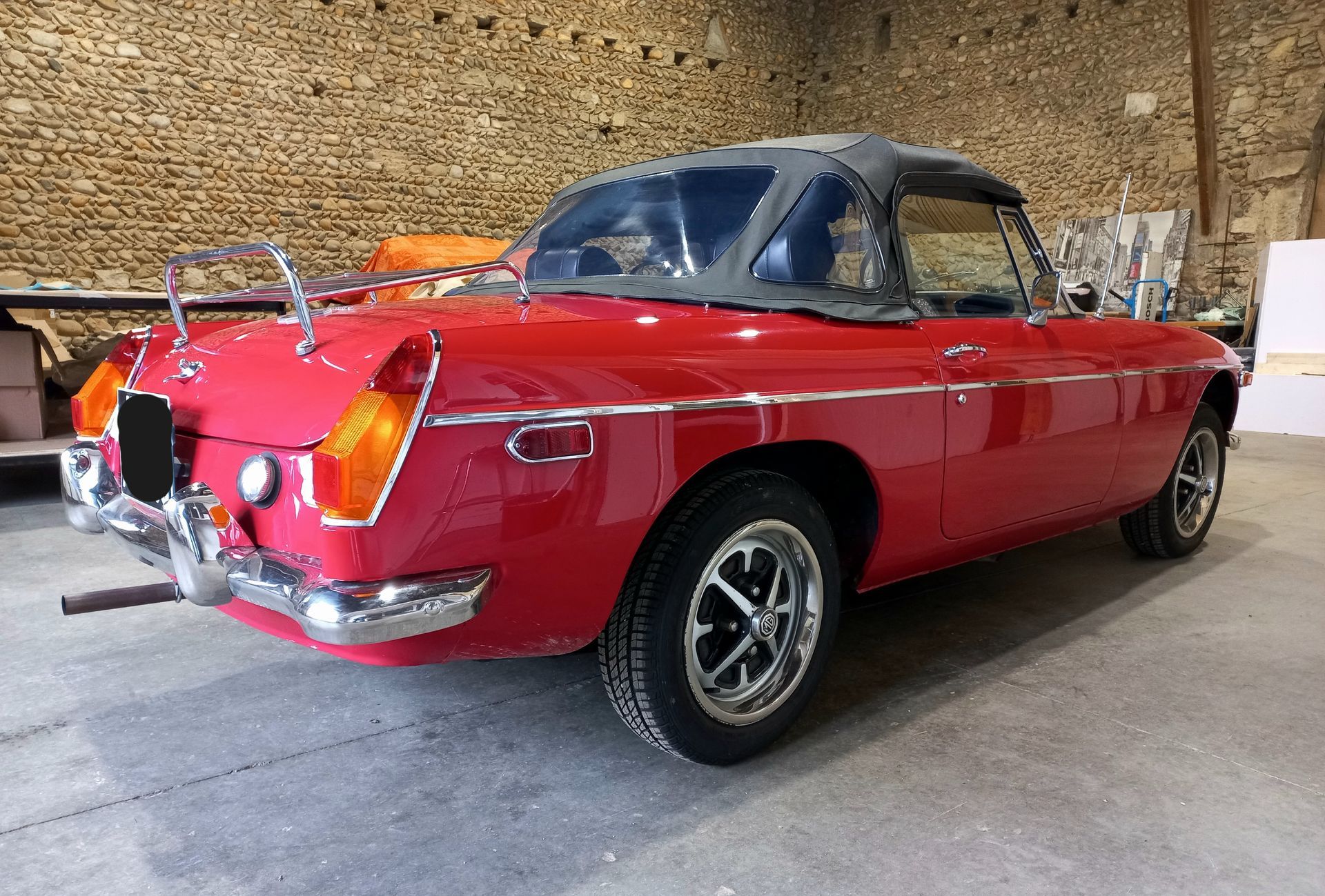 Voiture décapotable rouge classique garée à l'intérieur contre un mur de briques