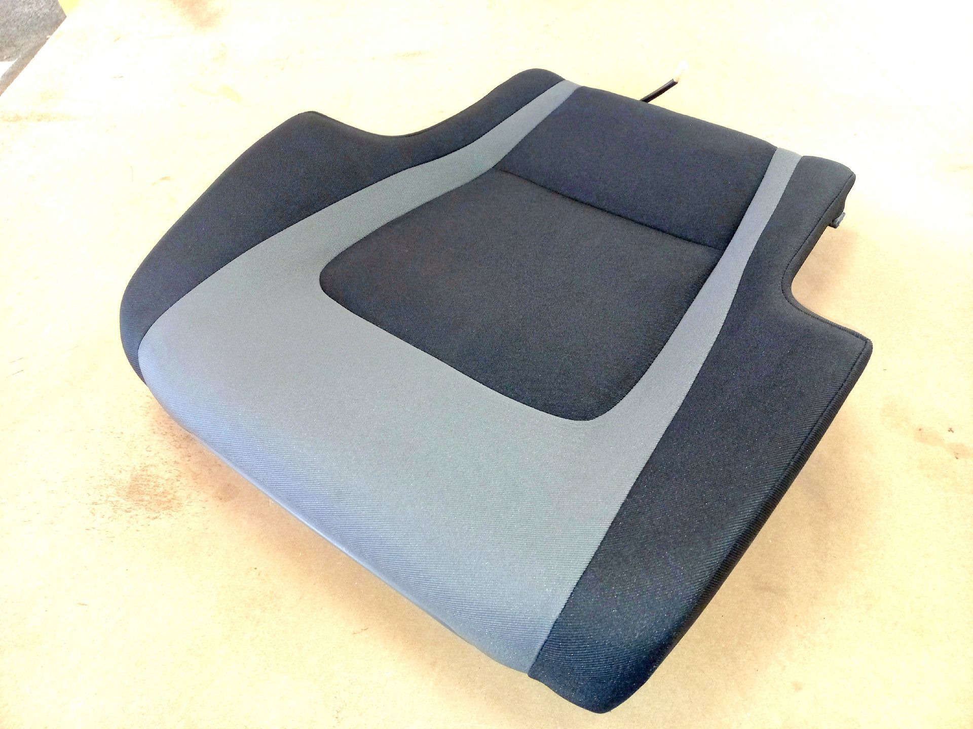 Coussin de siège auto rembourré bleu et gris sur une surface claire