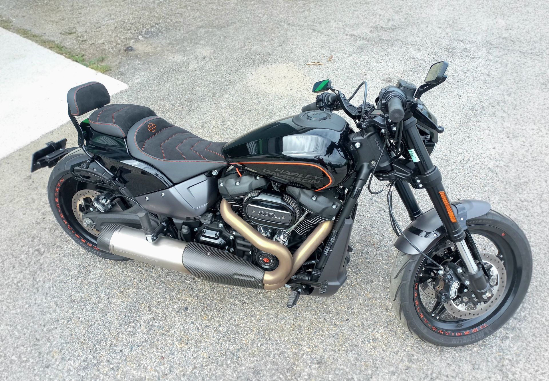 Moto cruiser noire avec des touches d'orange garée sur le trottoir, vue de côté