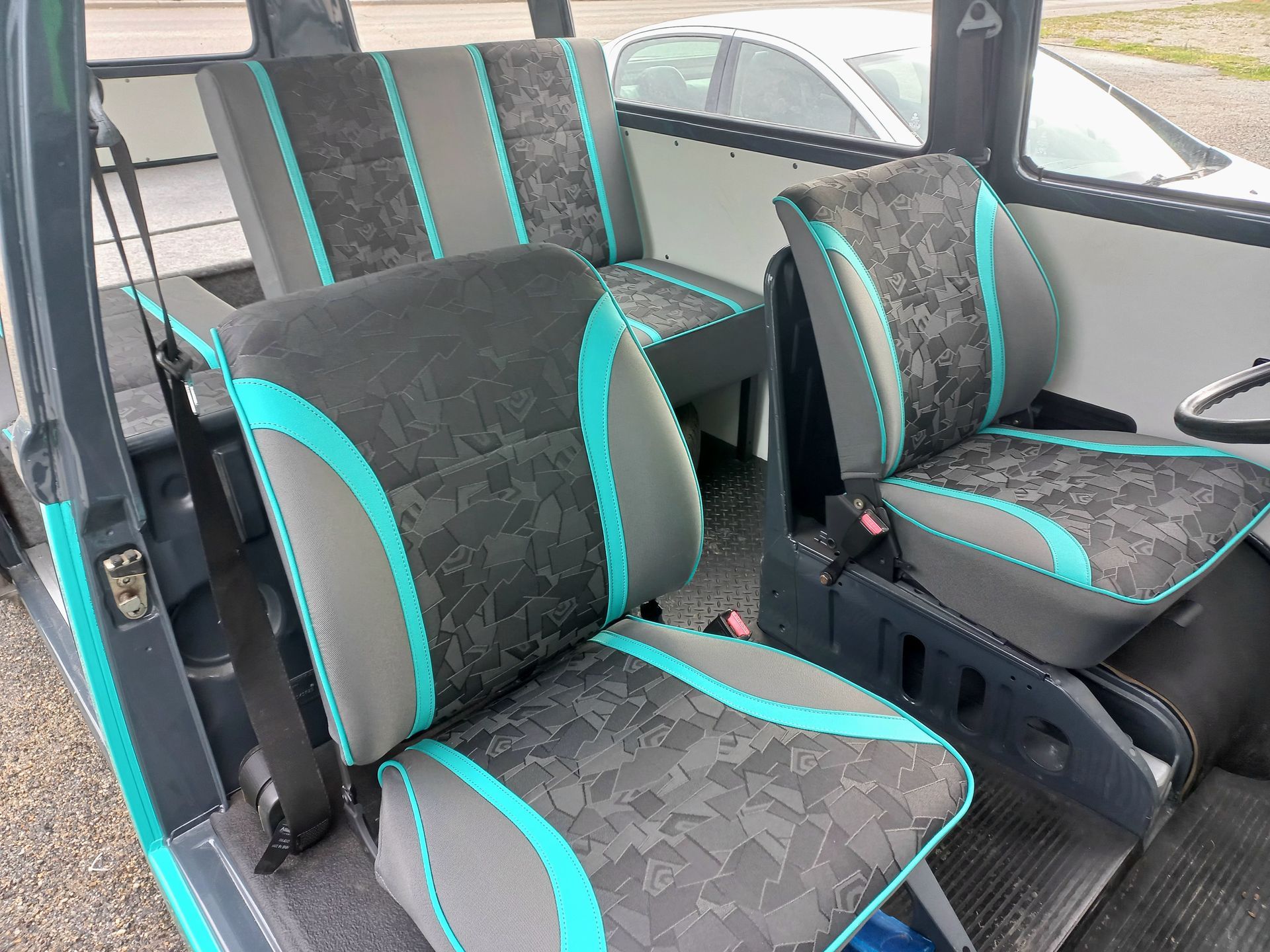 Trois sièges à motifs turquoise et noirs à l'intérieur d'une cabine de véhicule