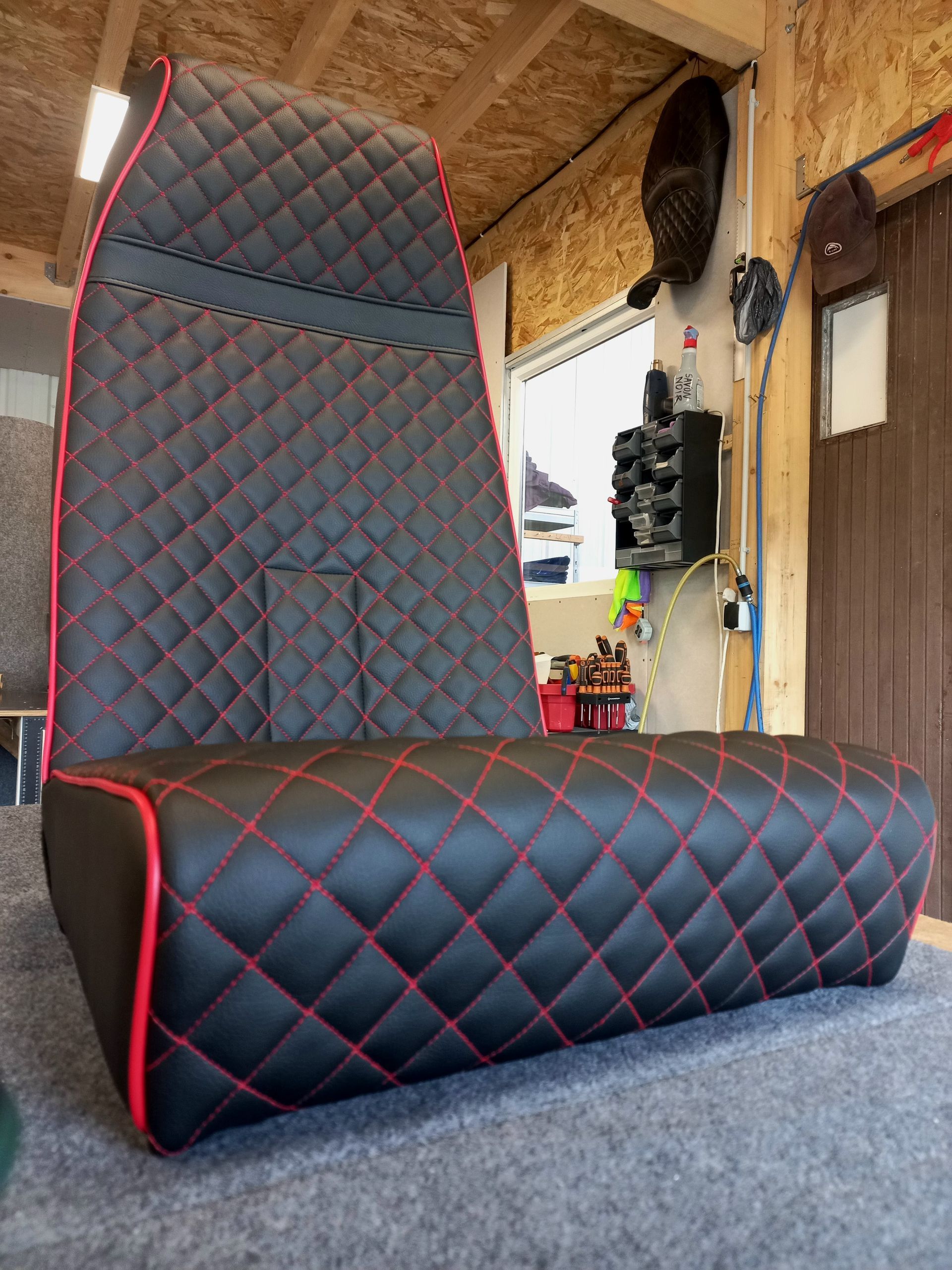 Siège matelassé noir avec garniture rouge dans un garage