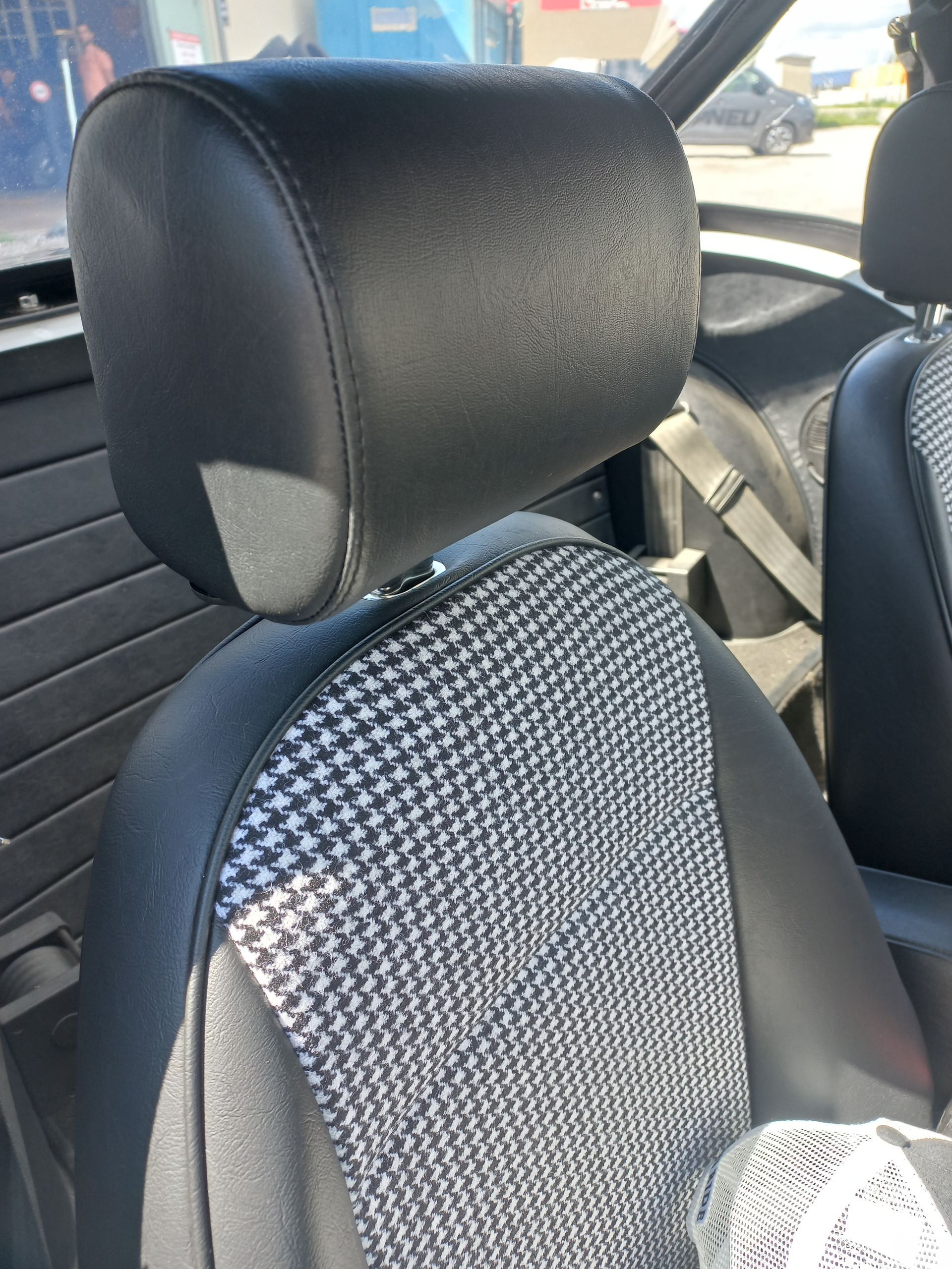 Siège auto avec appui-tête noir et housse de siège grise à motifs à l'intérieur d'un véhicule