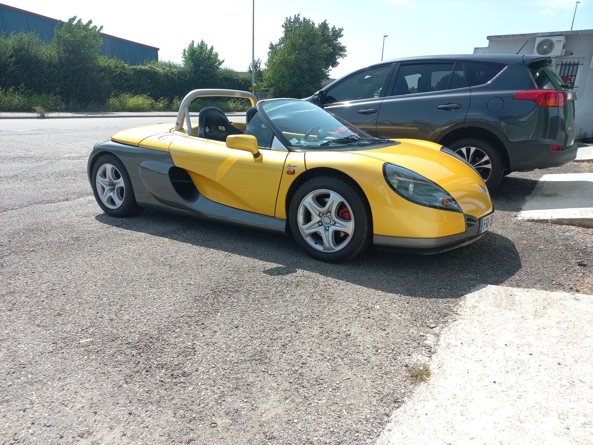 Une voiture de sport jaune garée sur un parking à côté d'un SUV noir par une journée ensoleillée